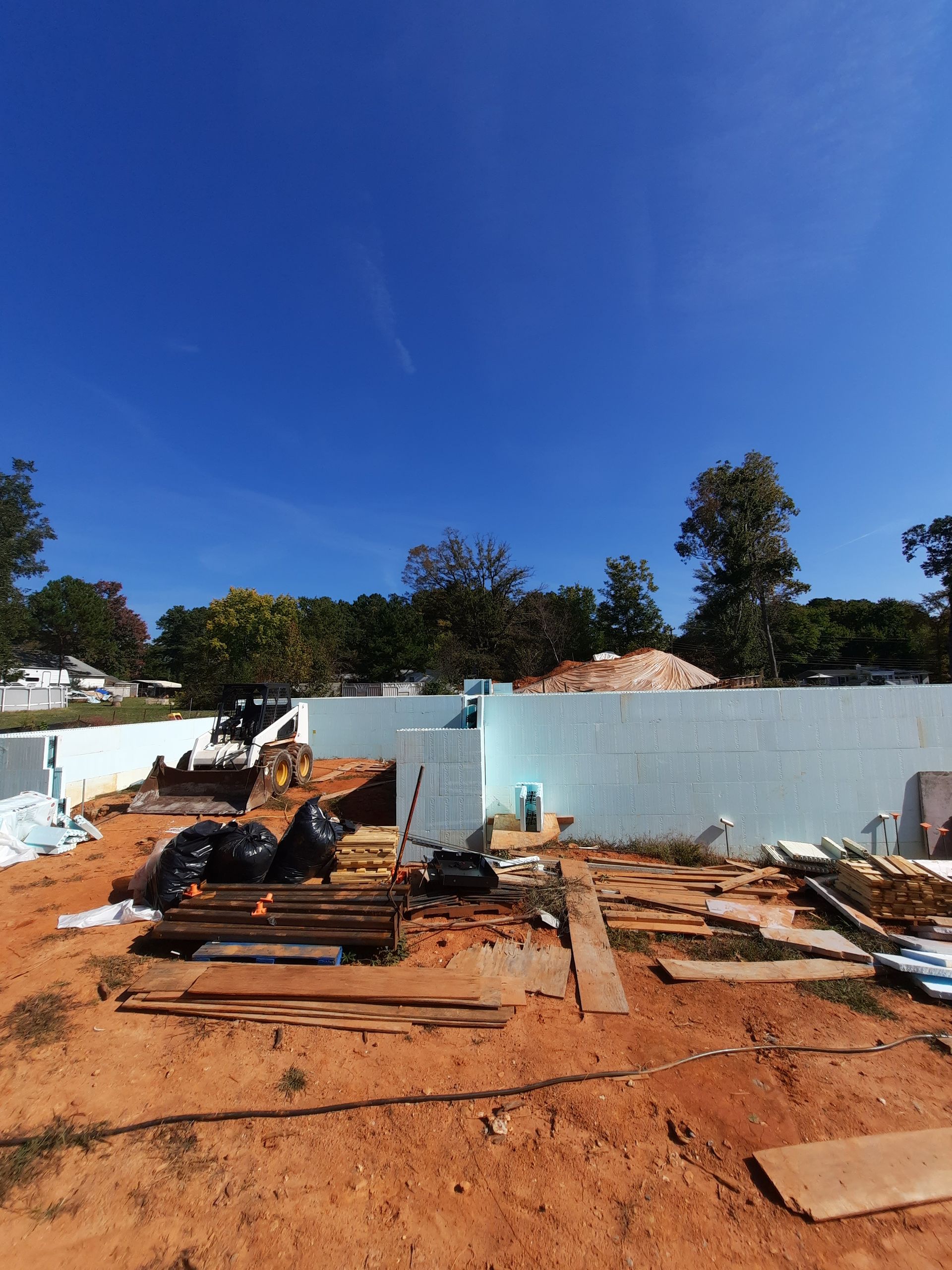 A construction site with a blue wall and a lot of dirt.