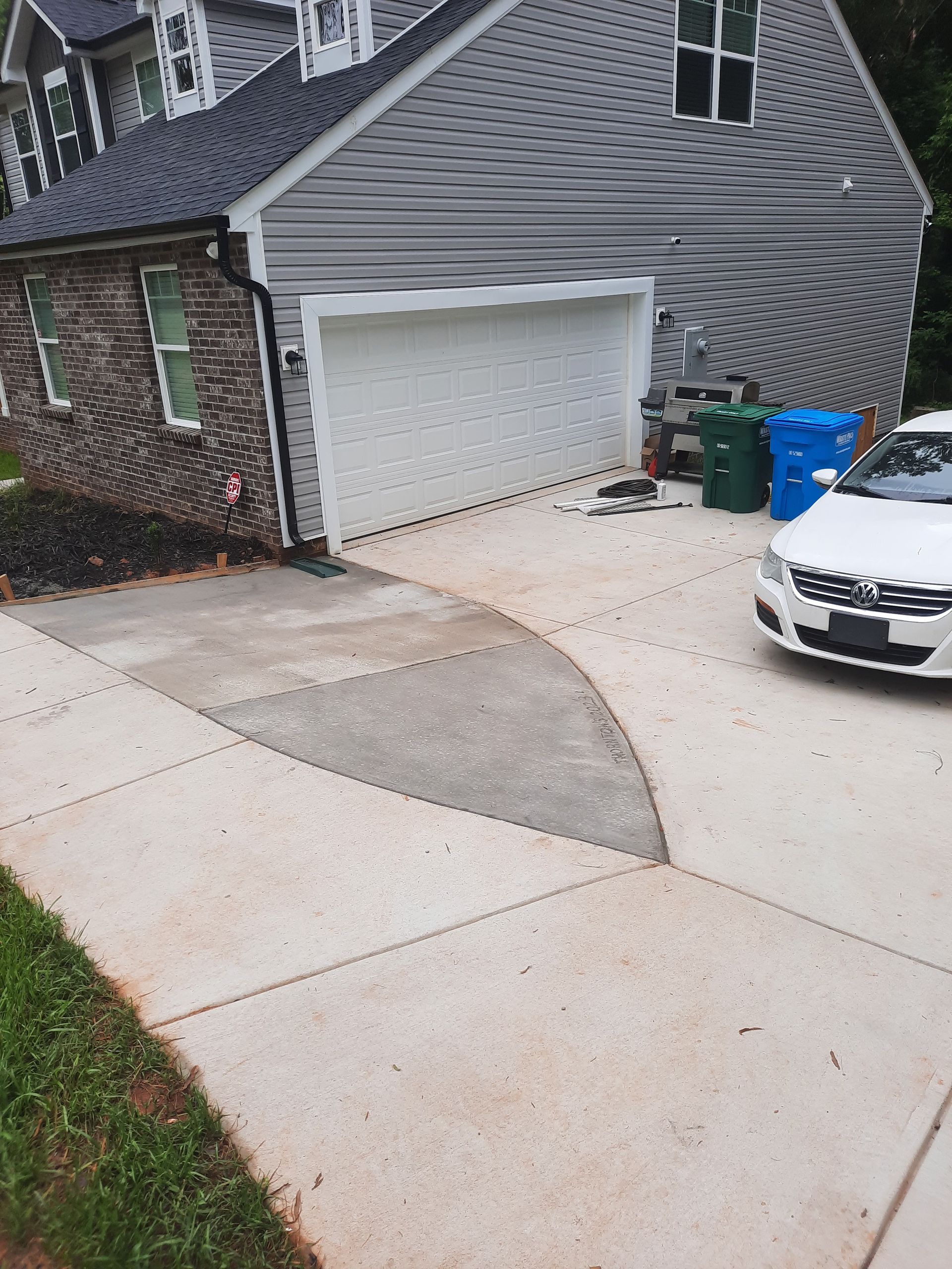 A white car is parked in front of a house with a garage door.