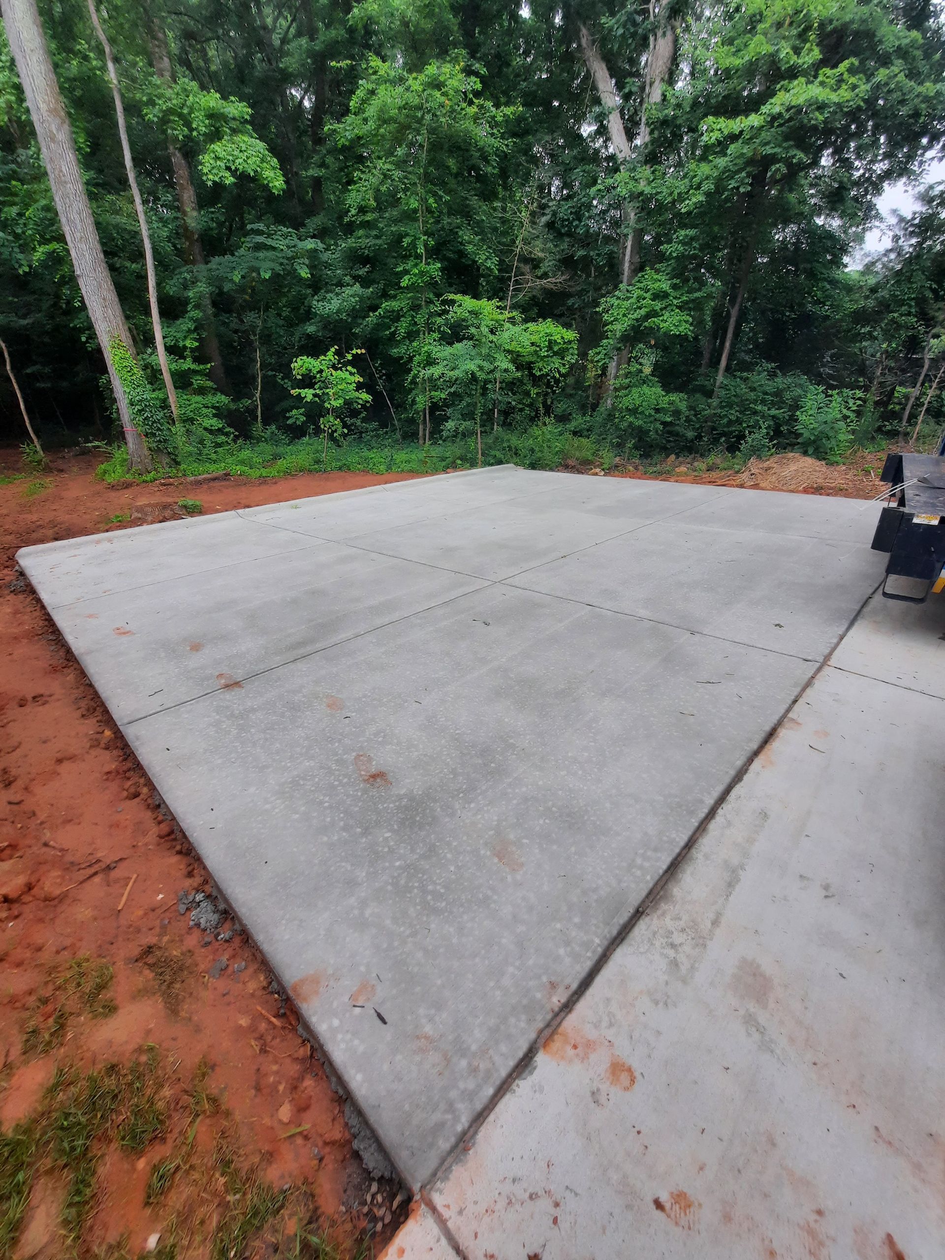 A concrete driveway in the middle of a forest with trees in the background.