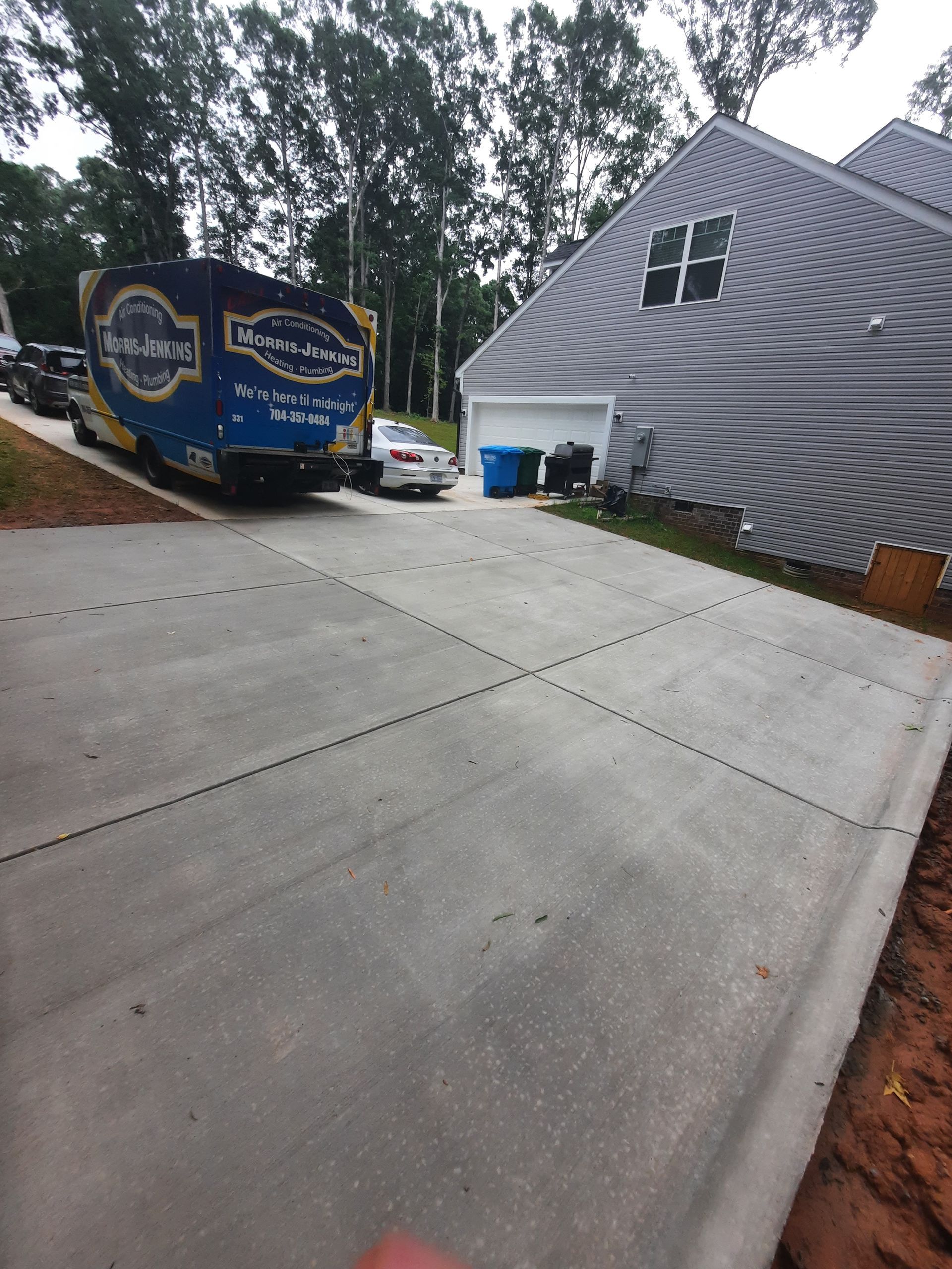 A truck is parked on the side of a driveway next to a house.