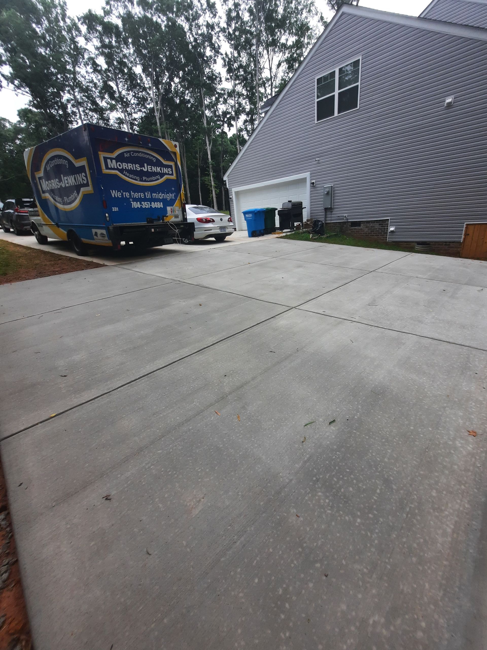 A blue truck is parked in a driveway in front of a house.