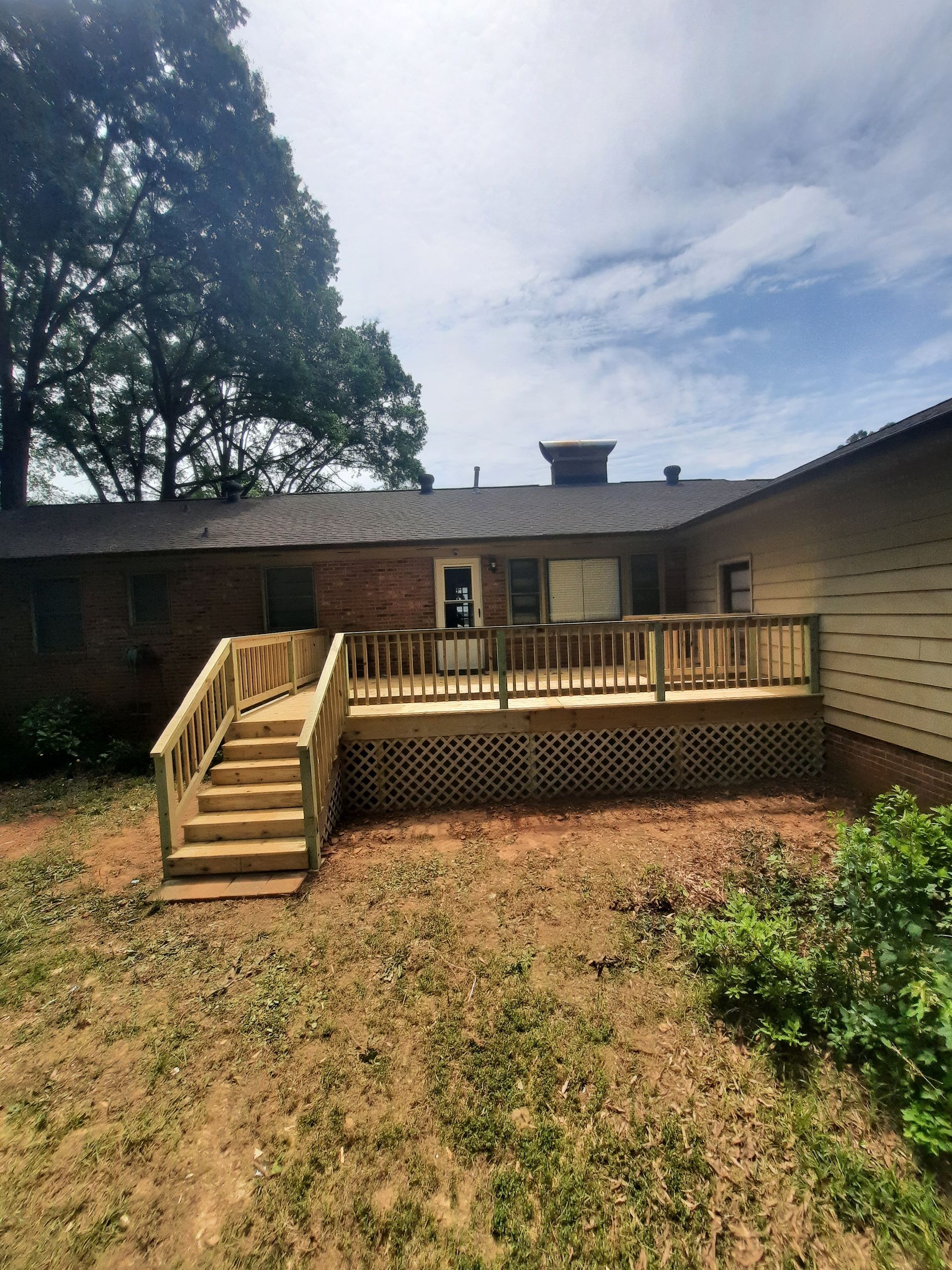 A wooden deck with stairs is in the backyard of a house.