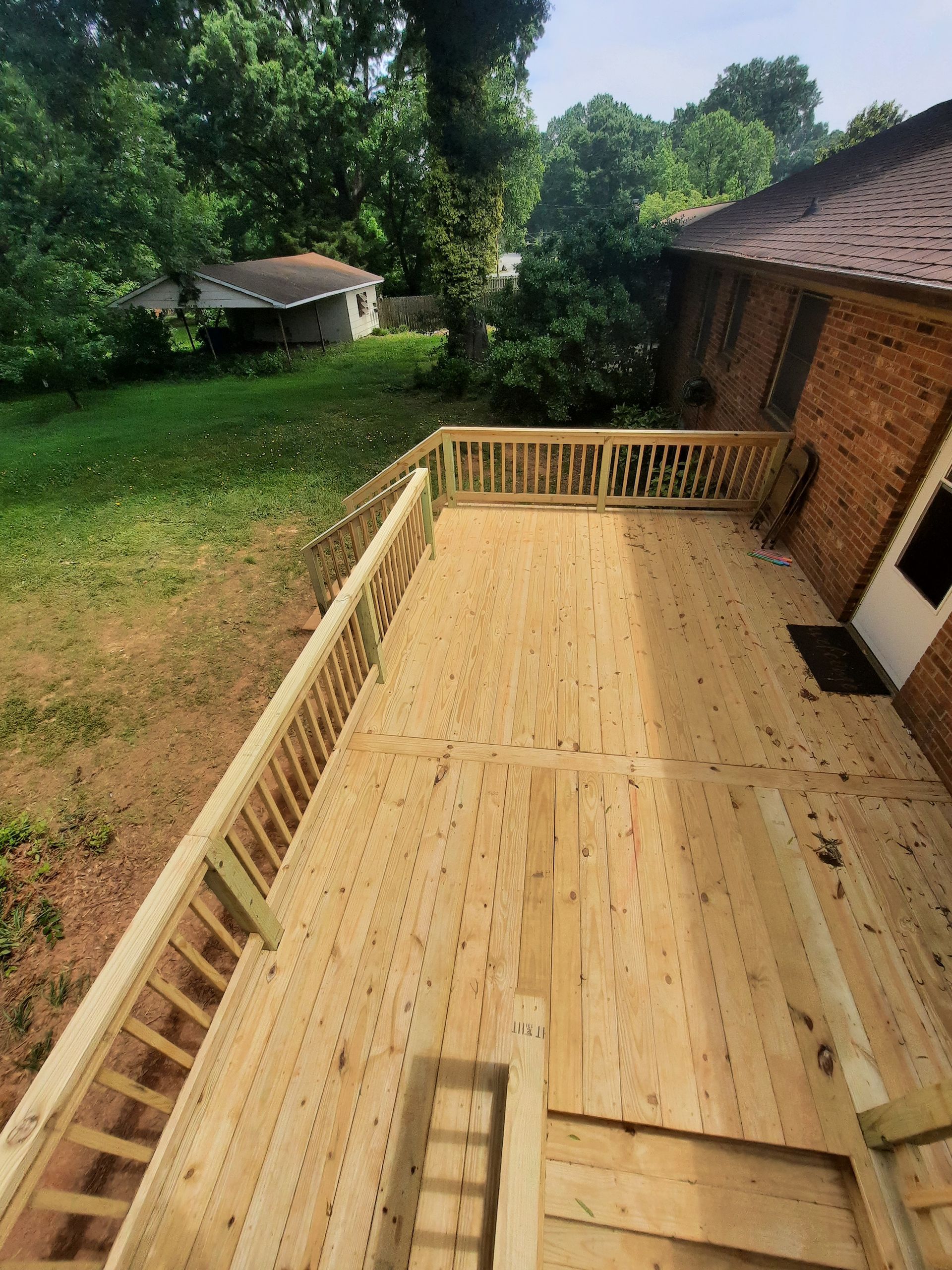 A wooden deck is being built in front of a brick house.