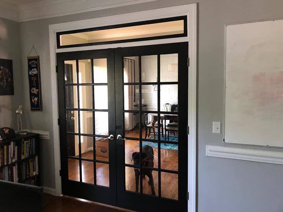 A dog is standing in a living room next to a french door.