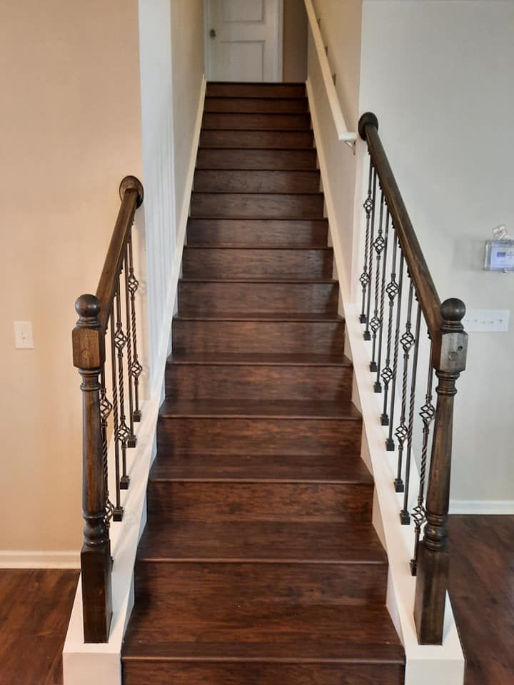 A wooden staircase with a wrought iron railing in a house.