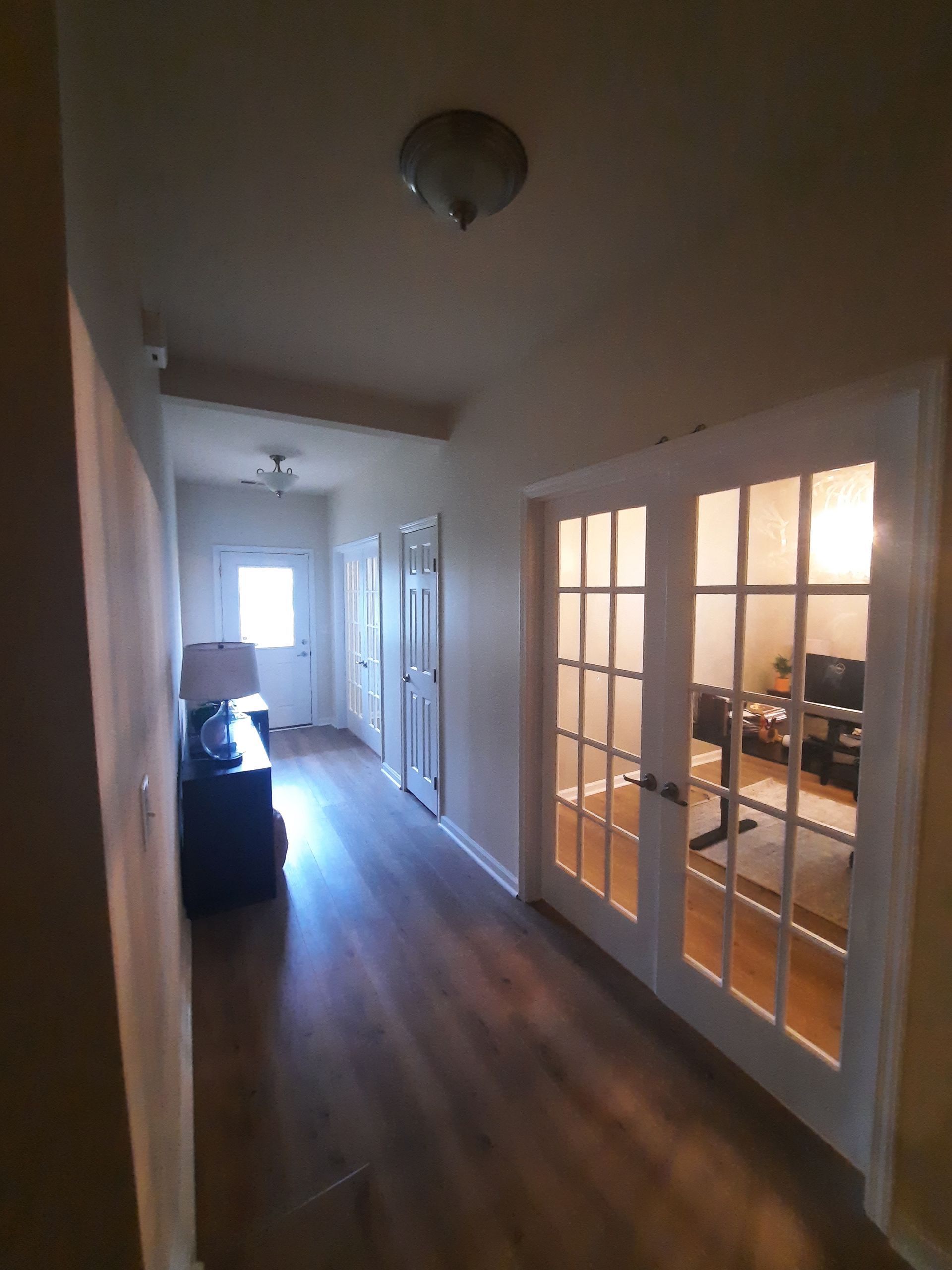 A hallway with french doors leading to a living room