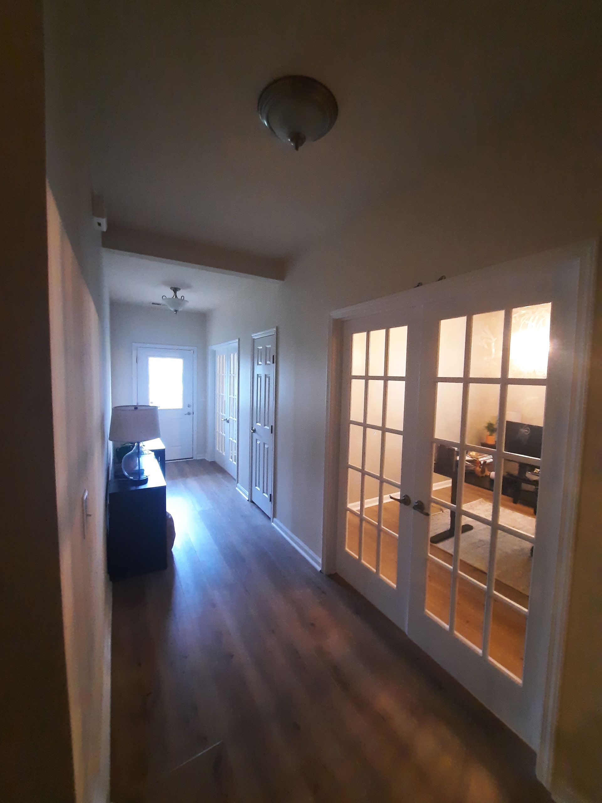 A hallway with french doors leading to a living room