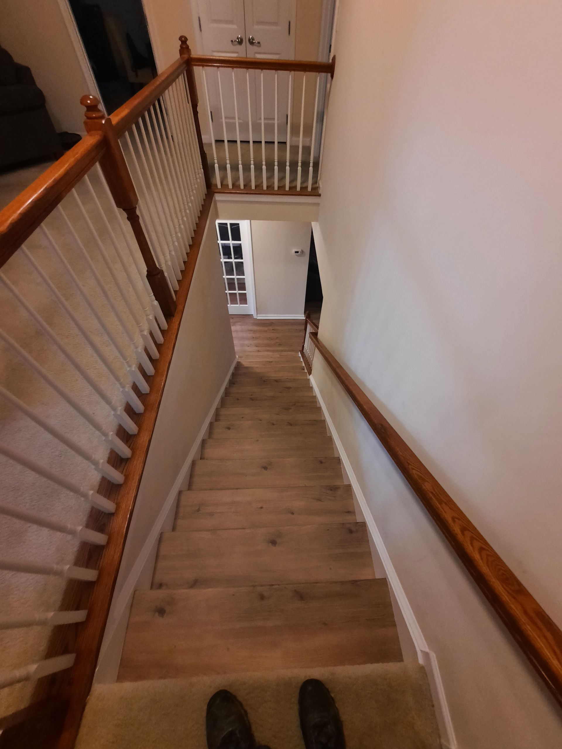 A person is standing at the bottom of a wooden staircase.