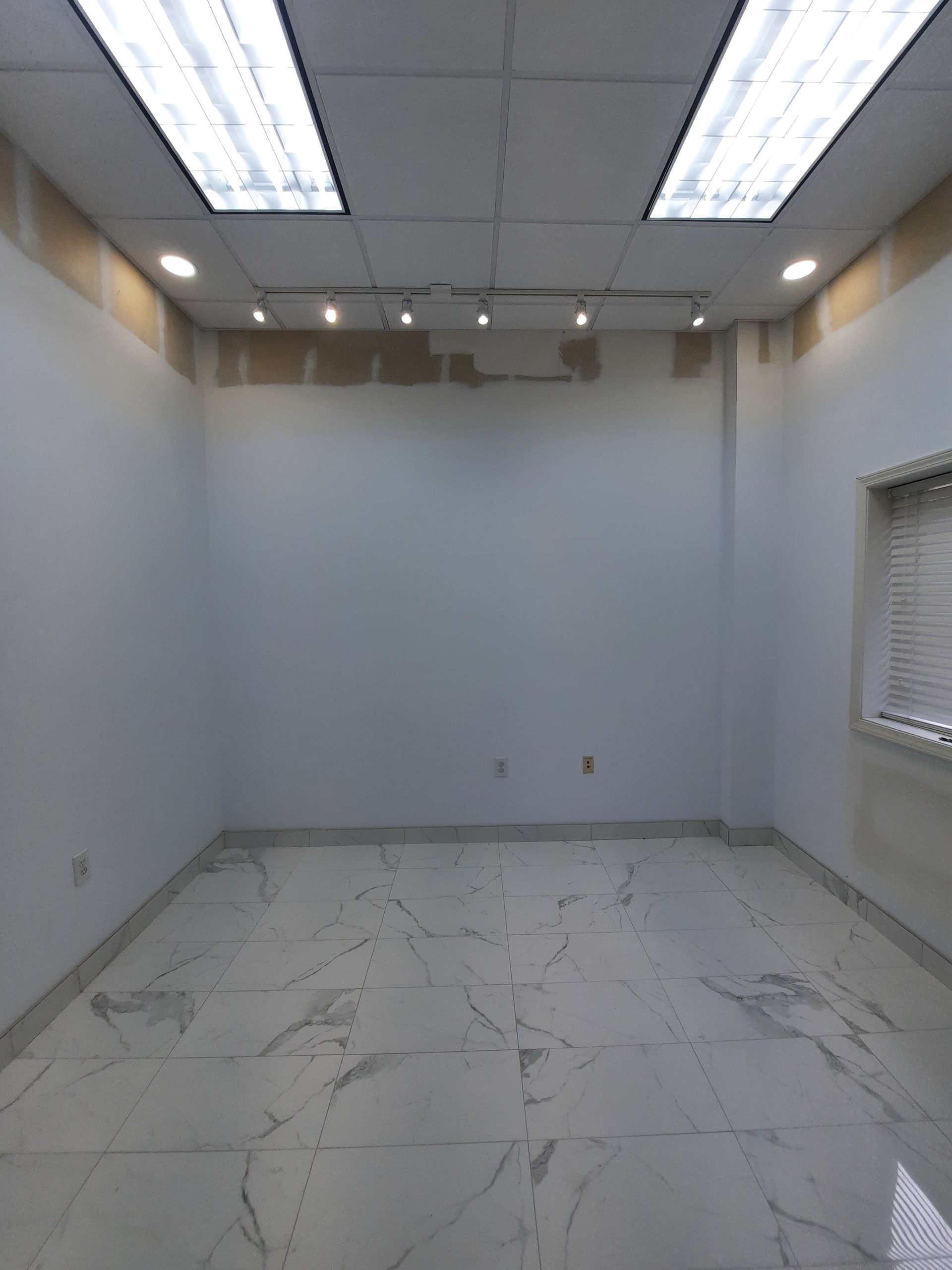 An empty room with white walls and marble floors