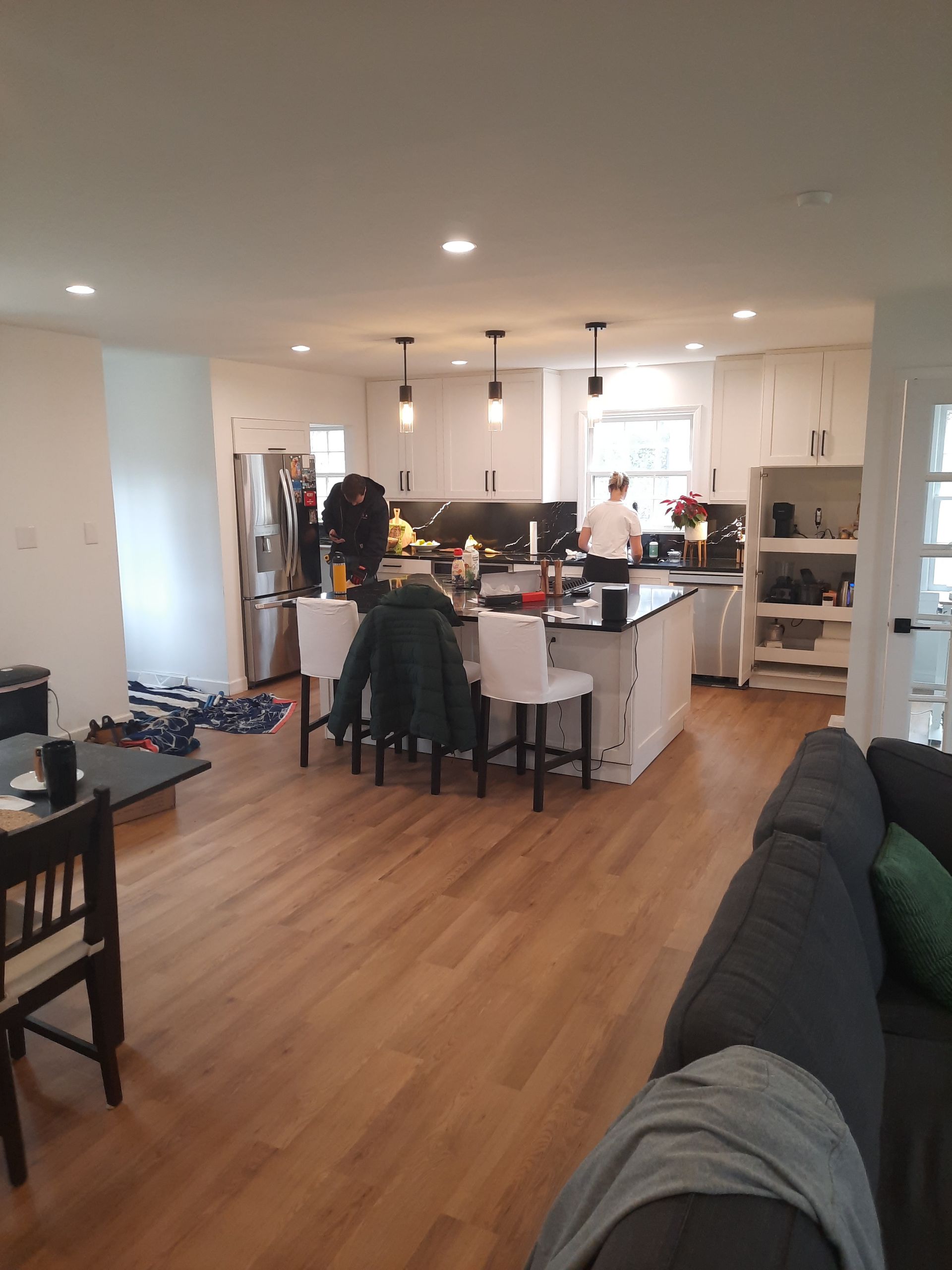 A living room with hardwood floors and a kitchen in the background
