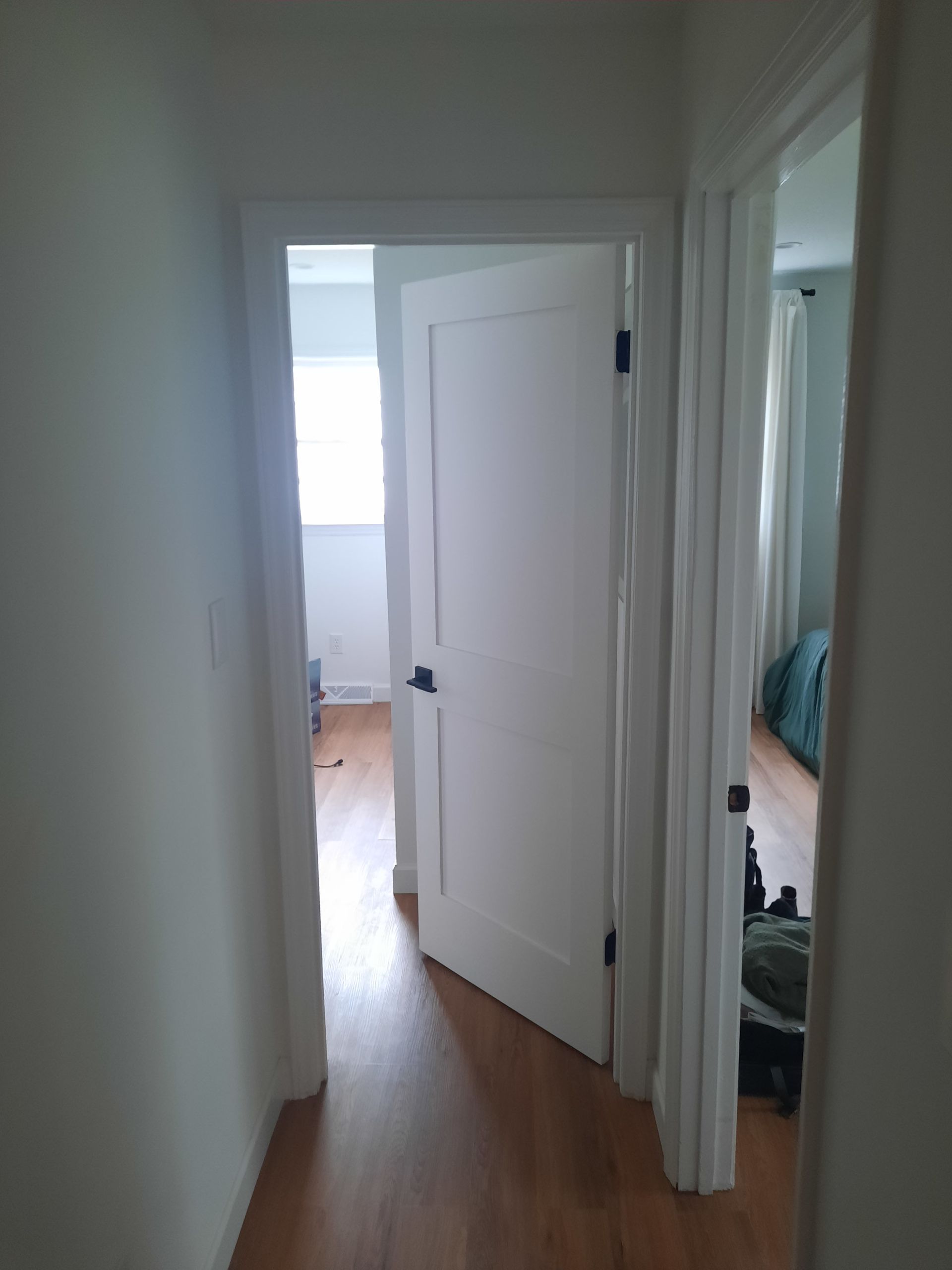 A hallway with a white door leading to a bedroom