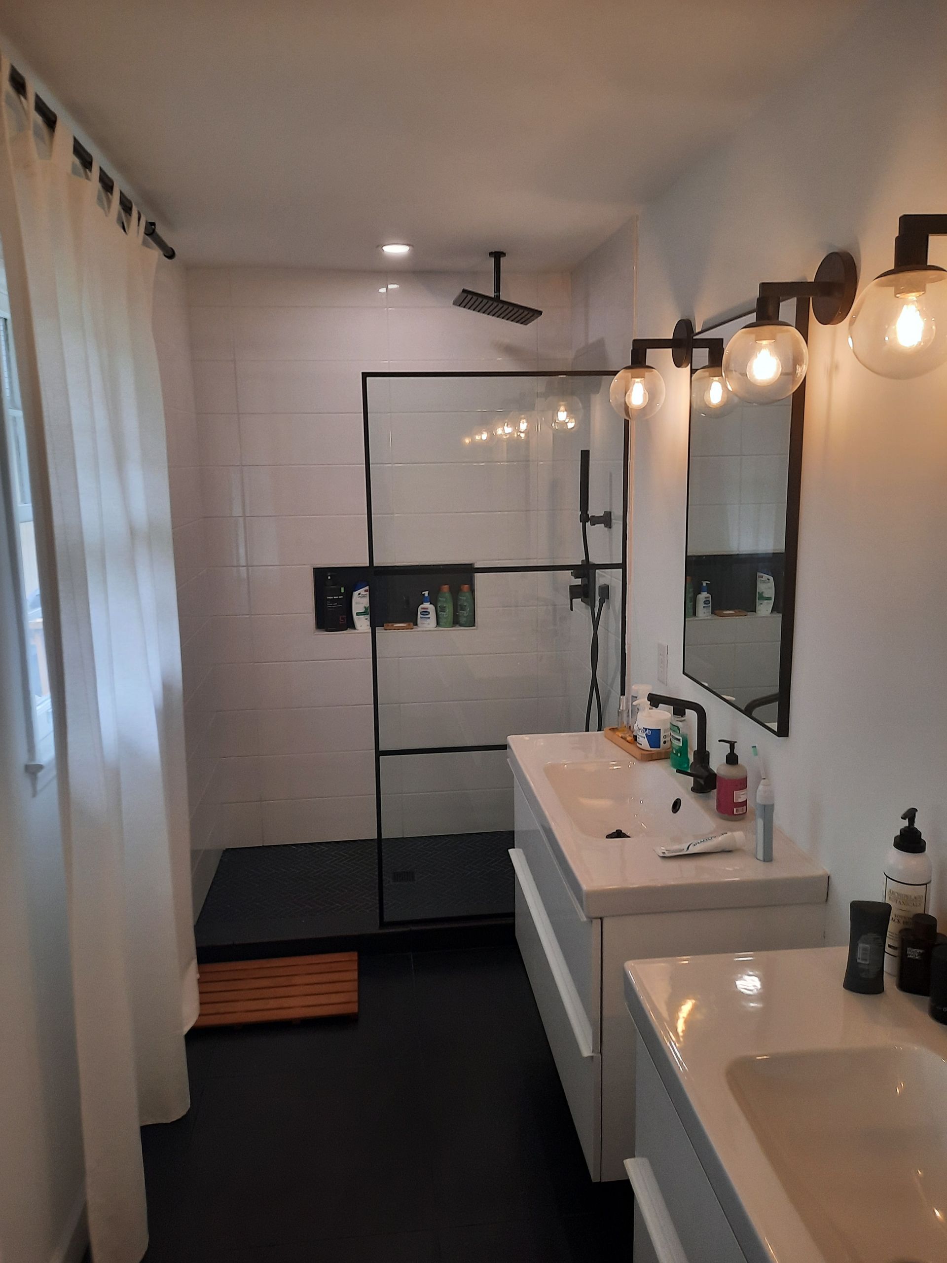 A bathroom with two sinks and a walk in shower.