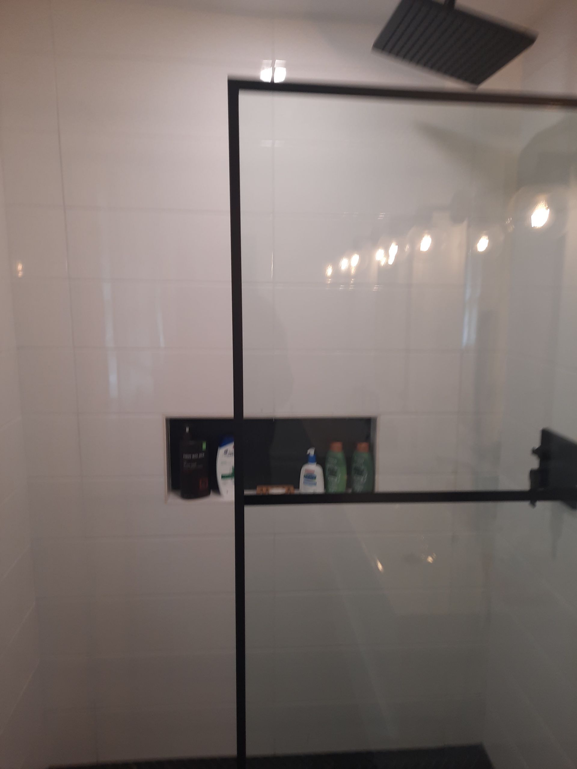 A bathroom with a glass shower door and a shower head.