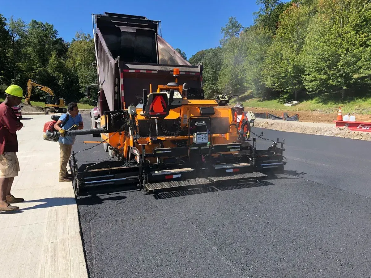 Asphalt paving machine laying fresh black asphalt. 