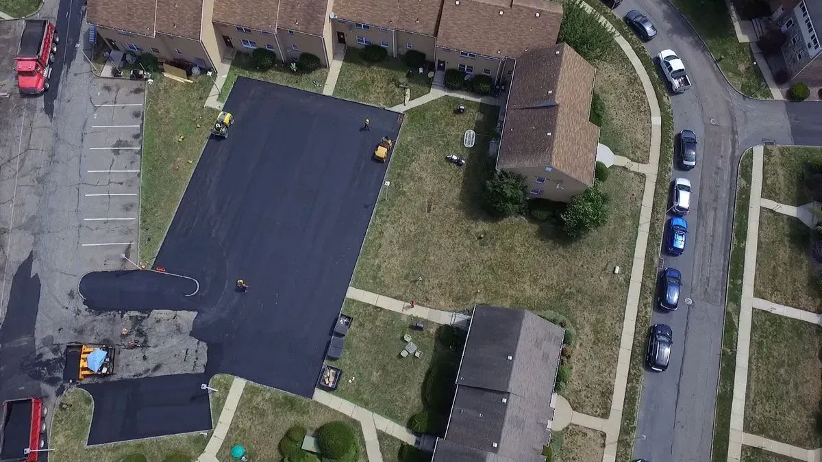 Aerial view of an asphalt parking lot being paved.