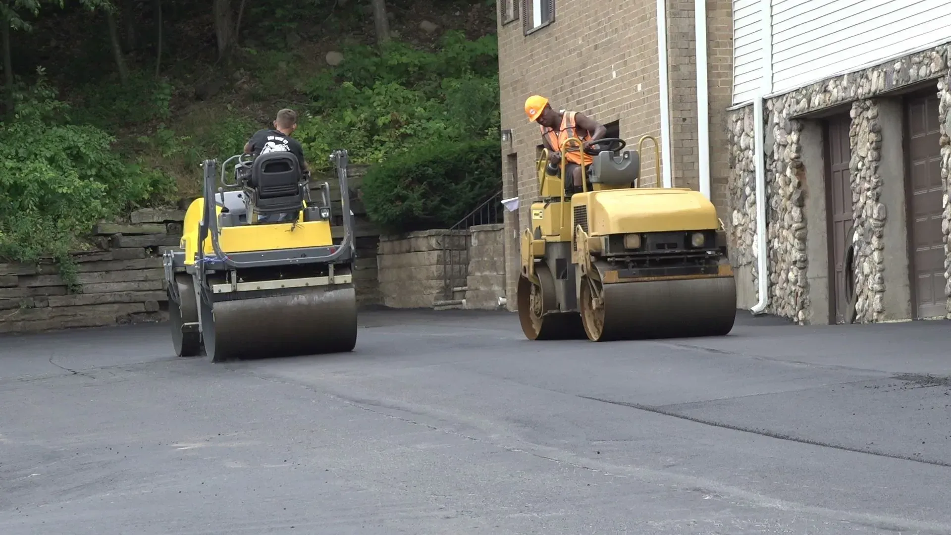 Two yellow road rollers compacting asphalt on a road.