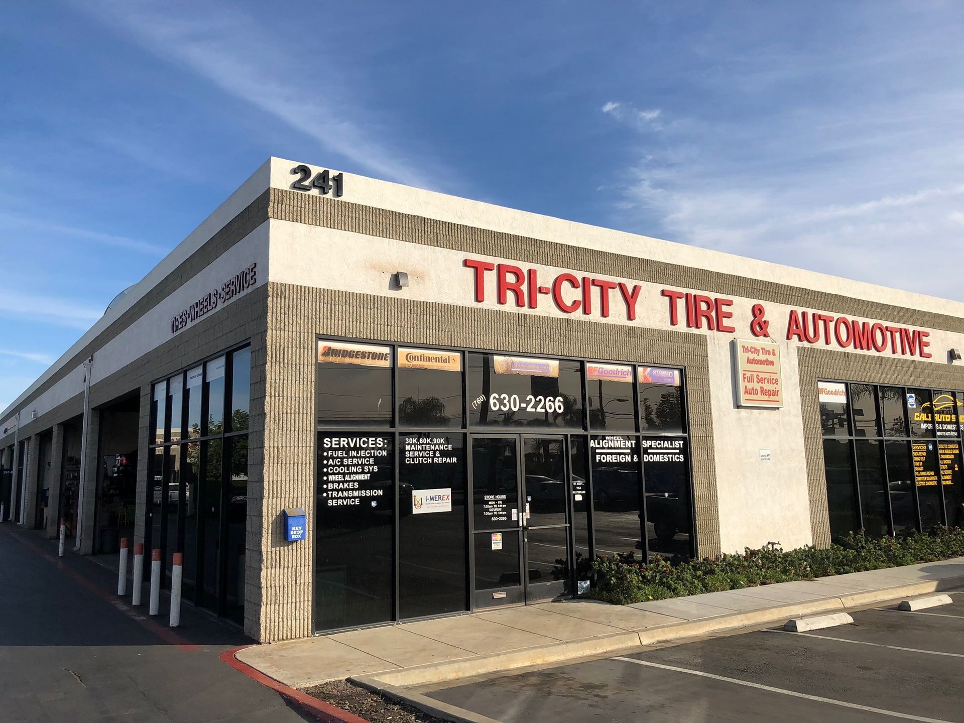 Tri-City Tire & Automotive storefront at 241, with dark windows, tan exterior, and blue sky.