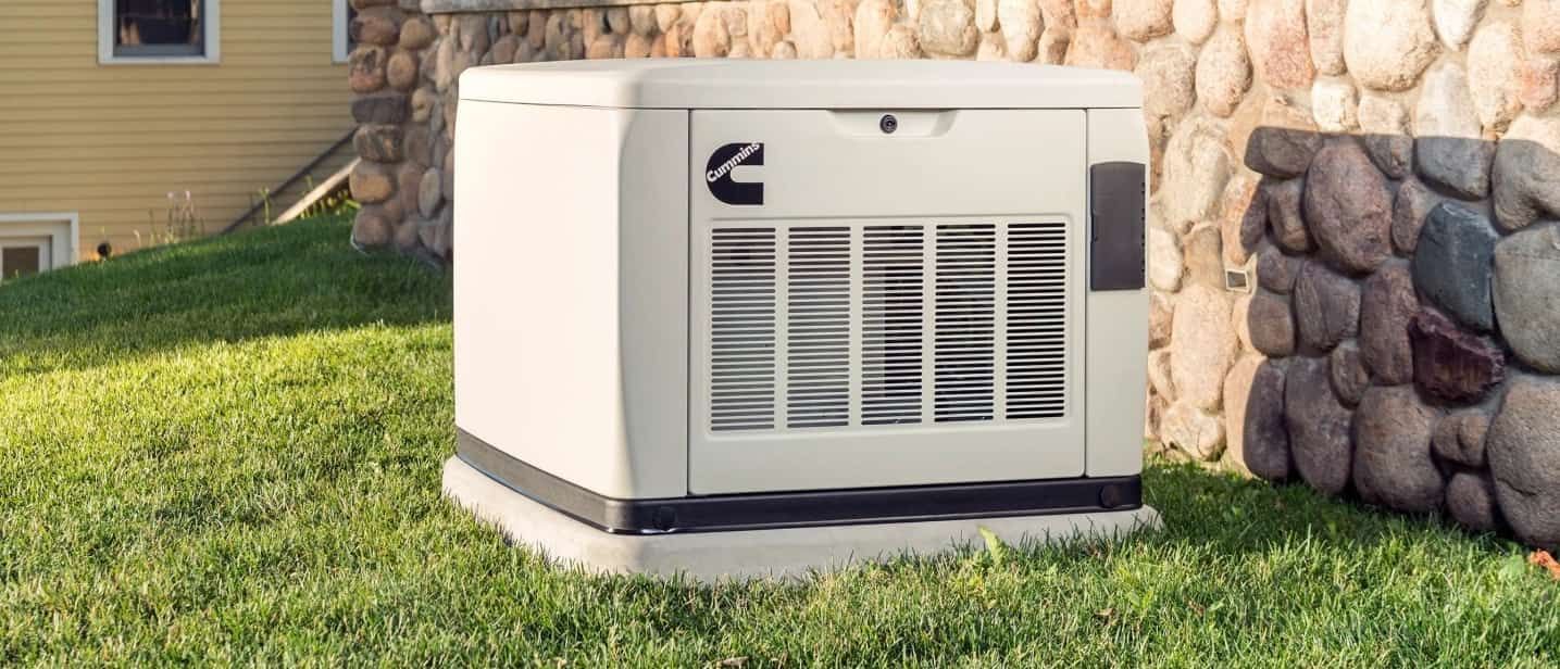 A generator is sitting in the grass in front of a house.