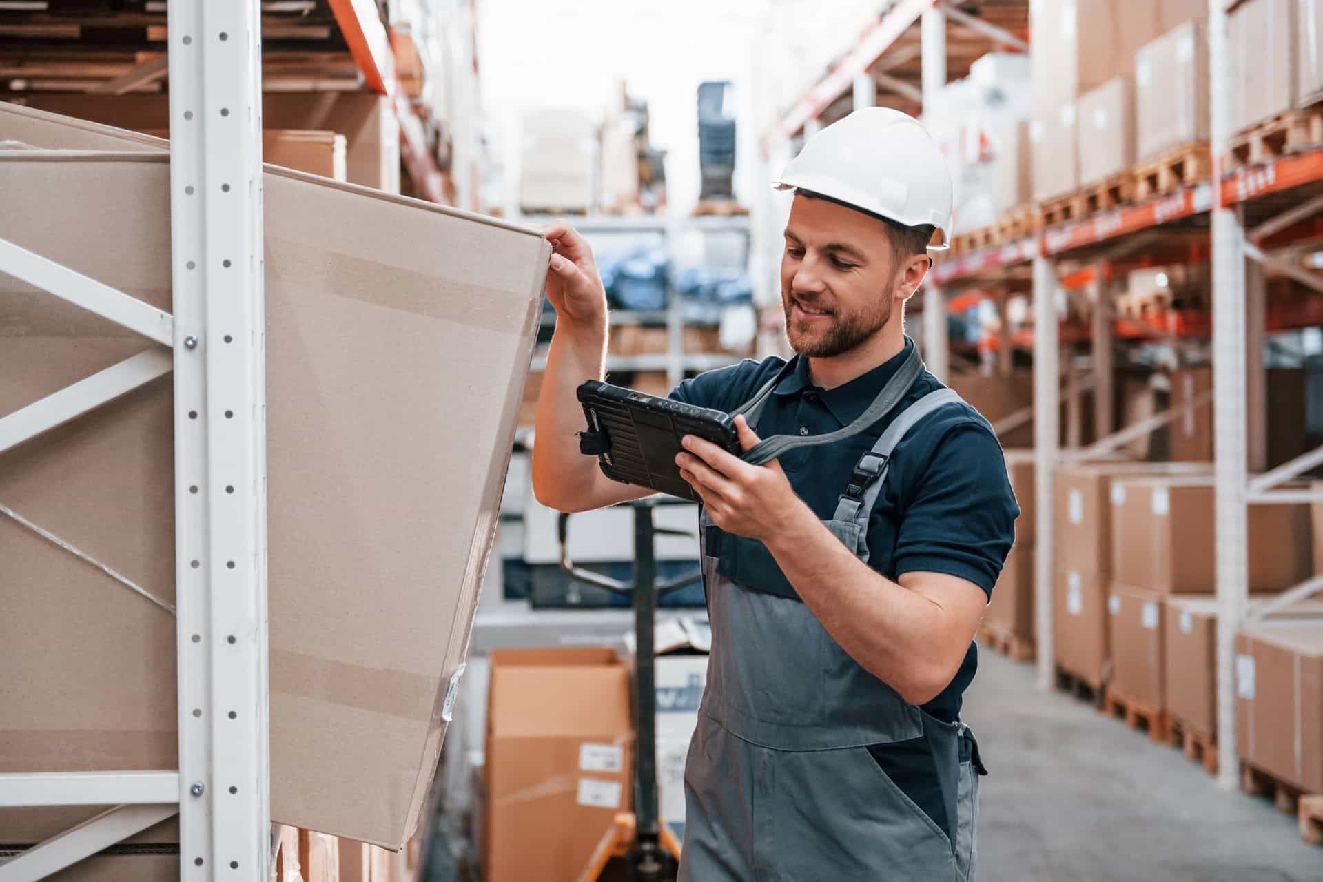 A man is using a tablet in a warehouse.