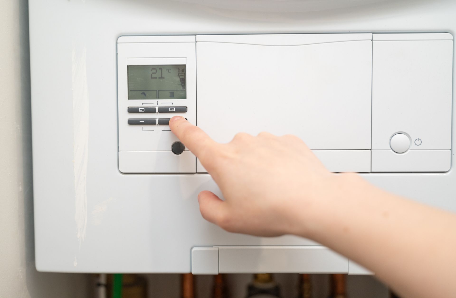 Hand adjusts thermostat set to 21°C for home heating.