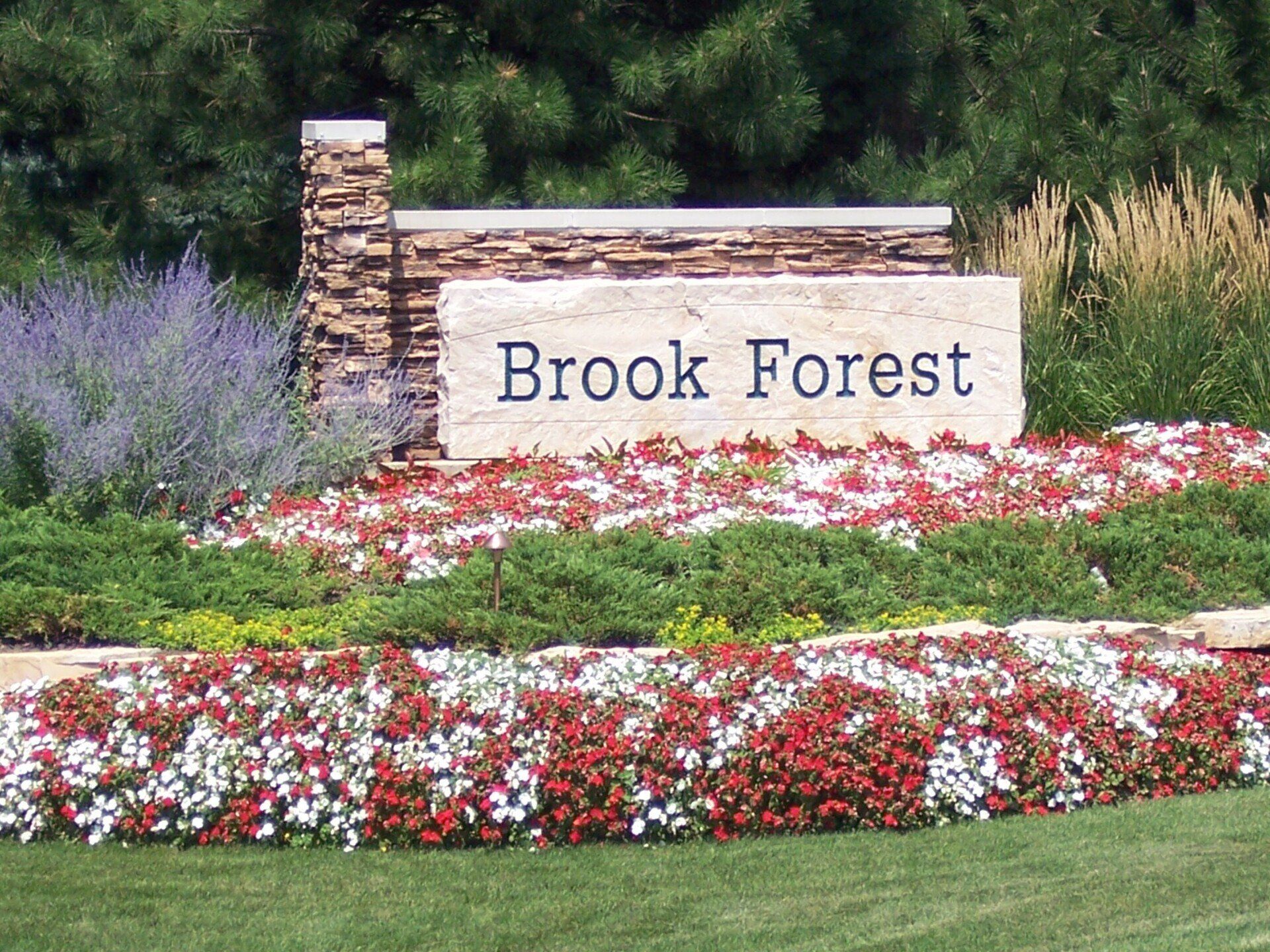 A sign for brook forest is surrounded by flowers