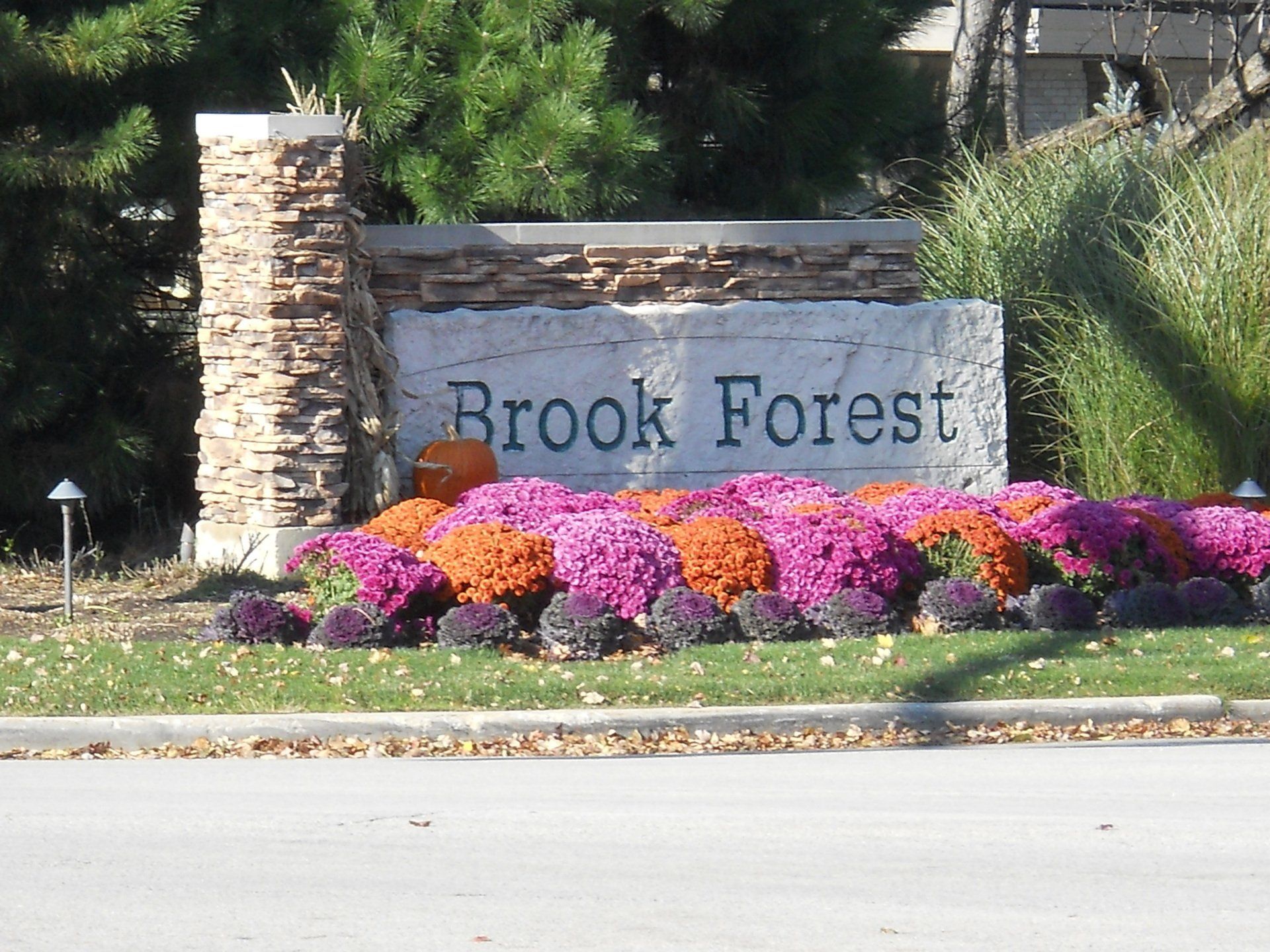 A sign for brook forest is surrounded by flowers