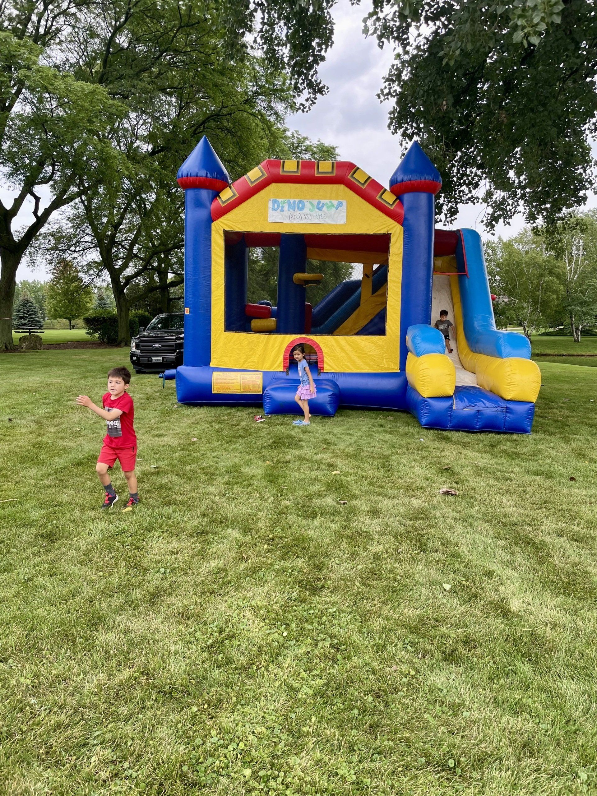 A boy and a girl are playing in front of a bouncy house.
