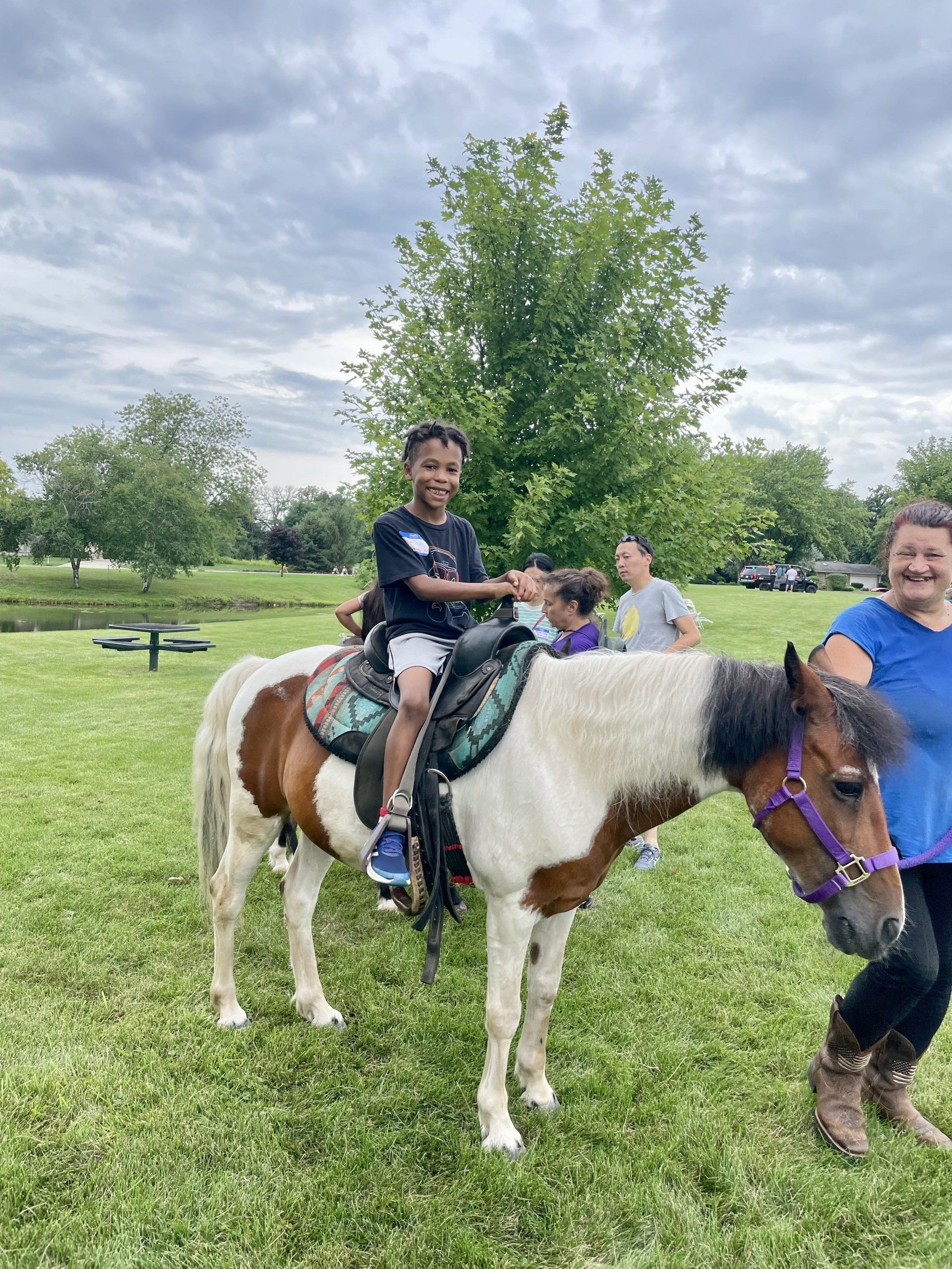A young boy is riding a pony in a park.