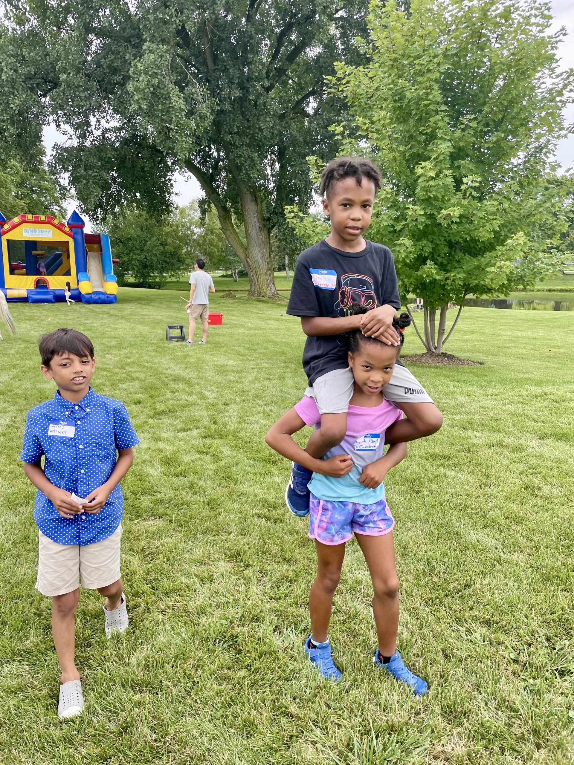 A boy is carrying a girl on his shoulders in a park.