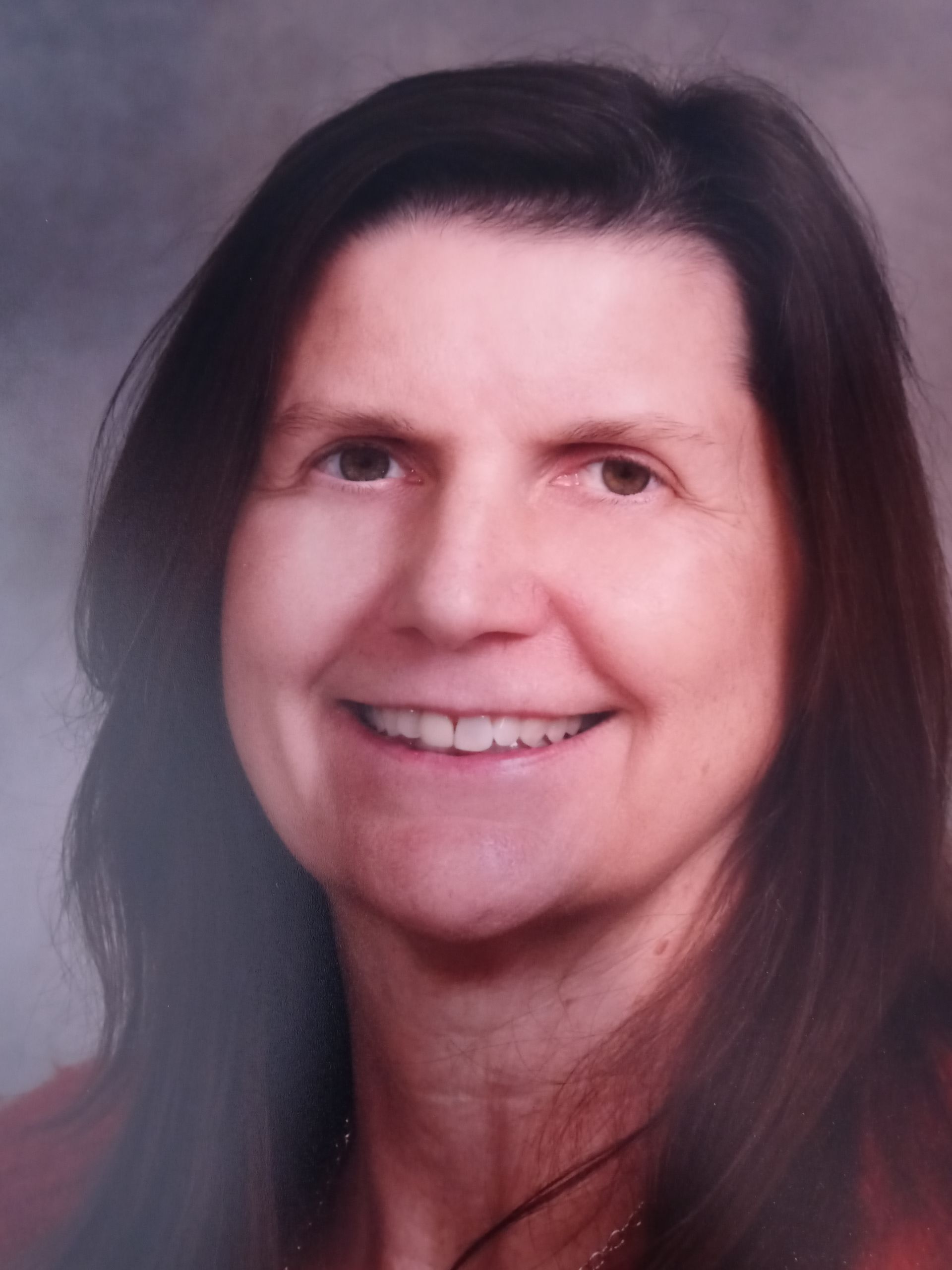 A woman with long dark hair is smiling for the camera.
