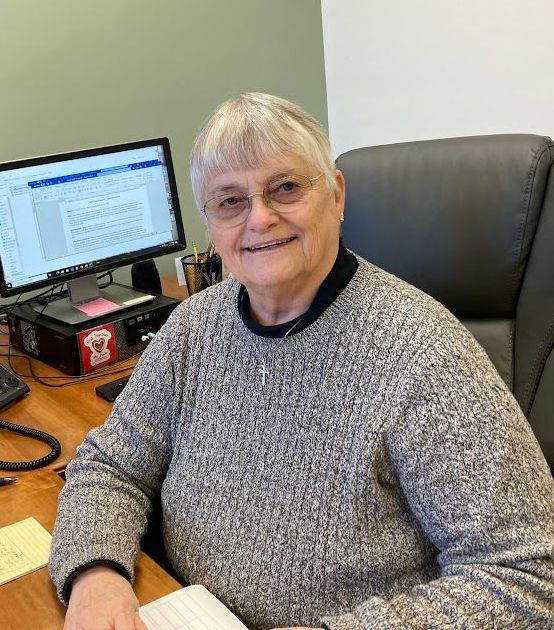 A woman is sitting at a desk in front of a computer.