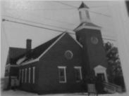 A black and white photo of a church with a steeple