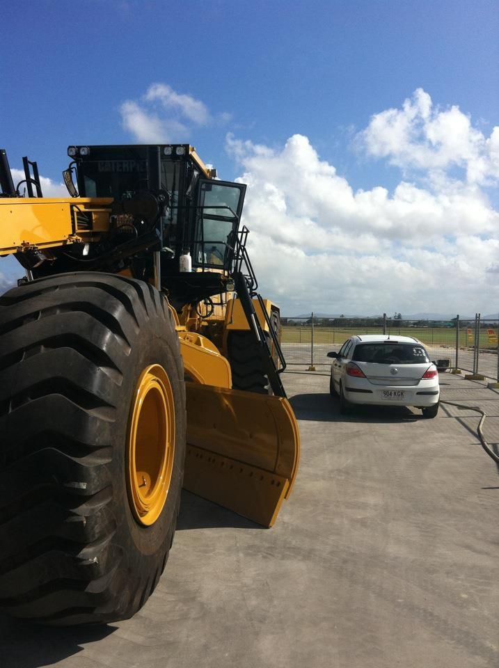 A Large Yellow Bulldozer Is Parked Next to A White Car β Epic Window Tinting in Glenella, QLD