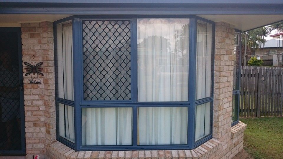 A Brick House with A Large Bay Window with A Blue Frame — Epic Window Tinting in Mackay, QLD