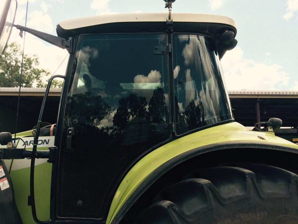 A Green Tractor Is Parked in Front of A Building — Epic Window Tinting in Mackay, QLD