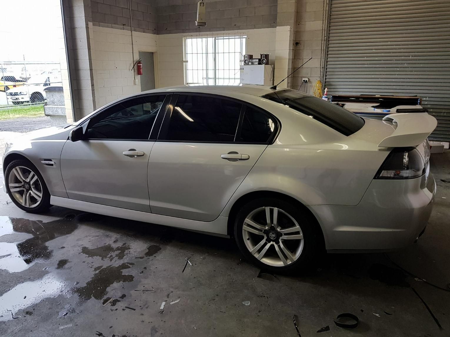 A White Car Is Parked in A Garage Next to A Window — Epic Window Tinting in Mackay, QLD