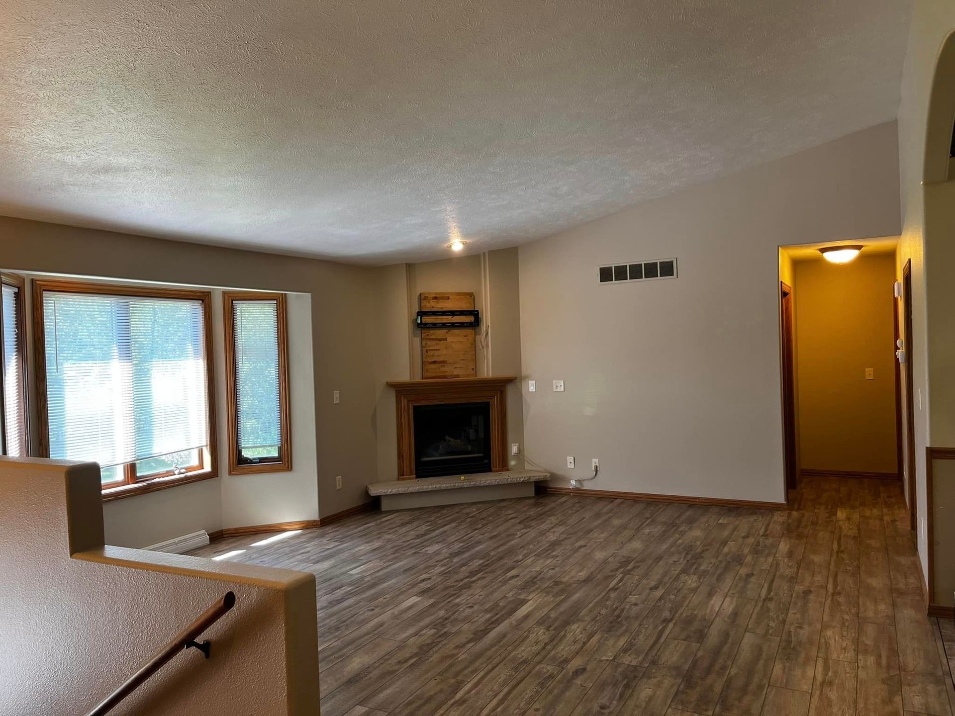 An empty living room with hardwood floors and a fireplace.