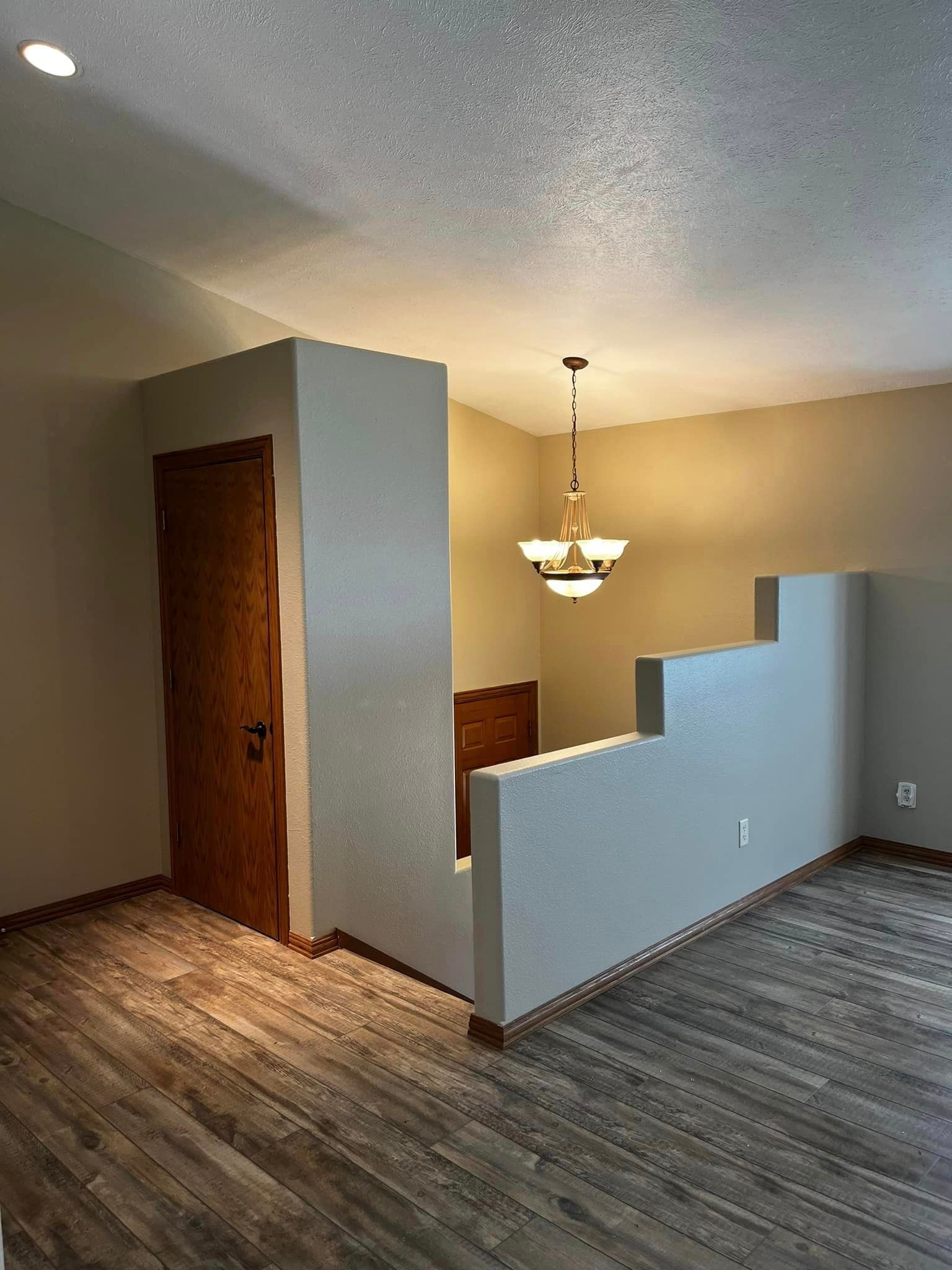 A living room with hardwood floors and a chandelier hanging from the ceiling.