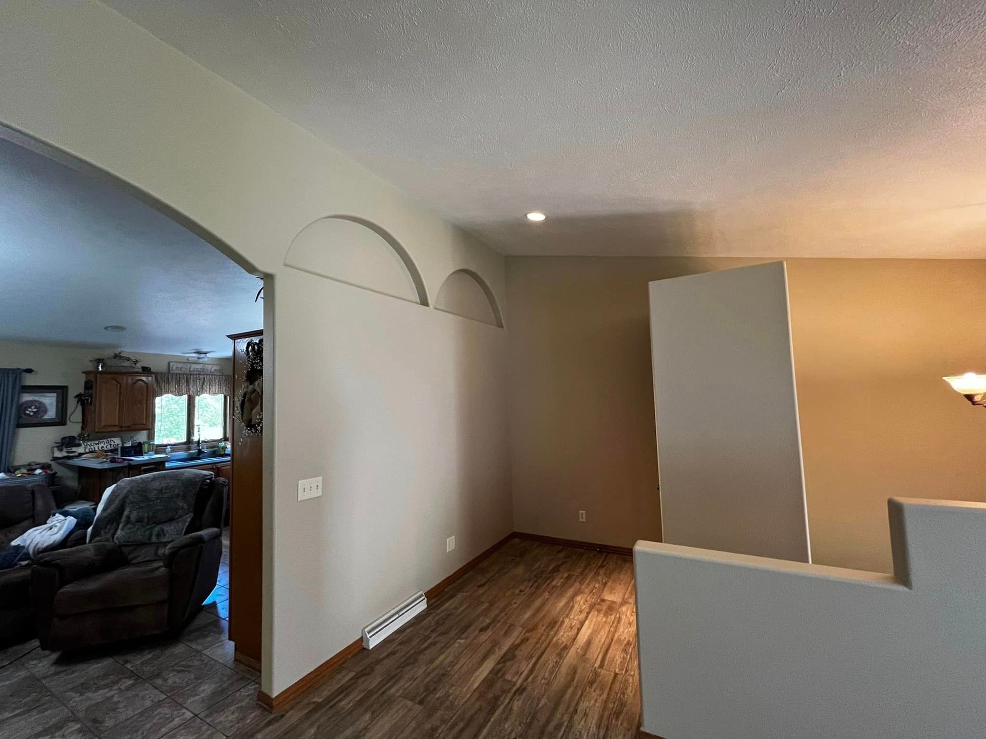 A living room with hardwood floors and a staircase leading to a dining room.