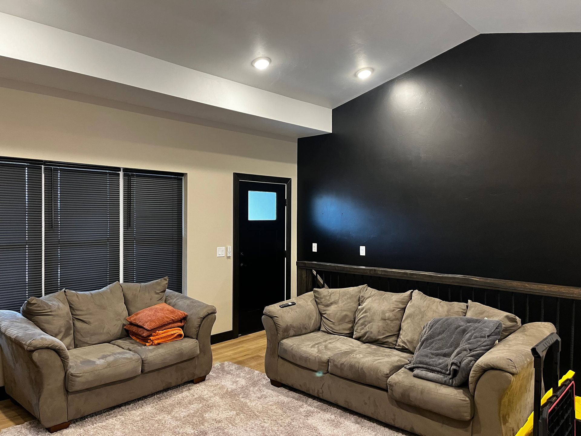 A living room with two couches and a black wall.
