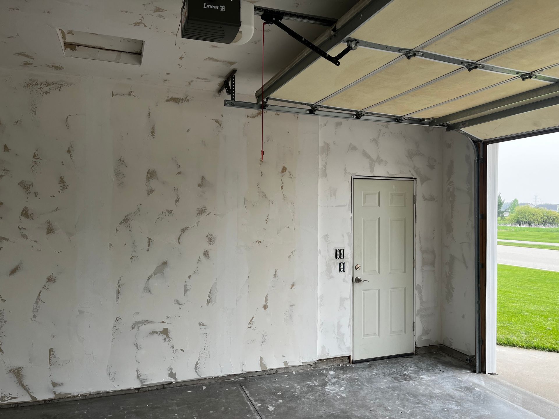 An empty garage with a door open and a garage door open.