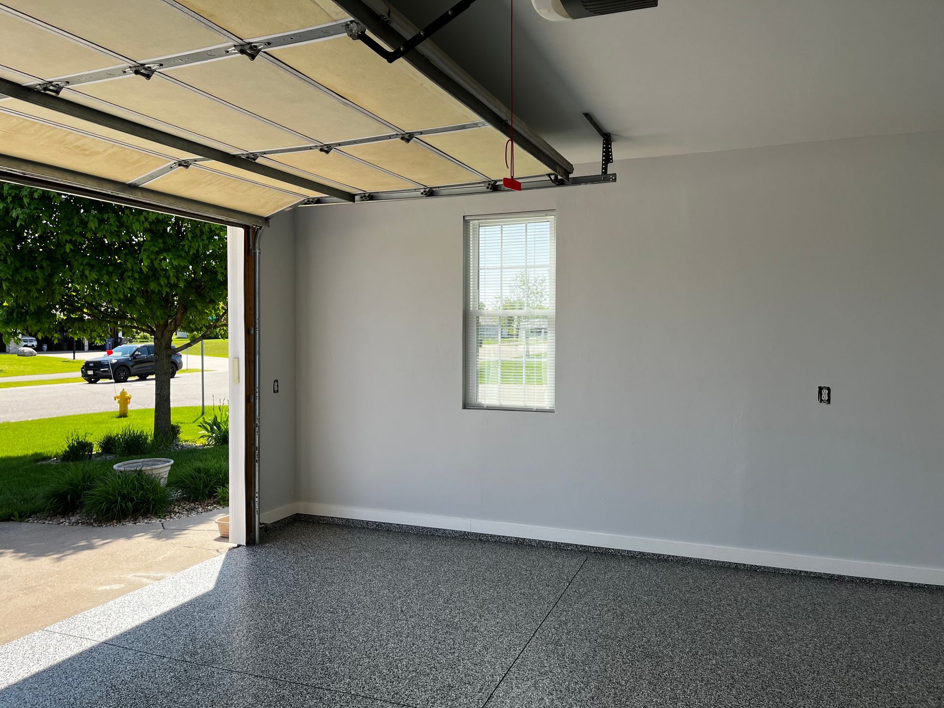 An empty garage with the door open and a window.