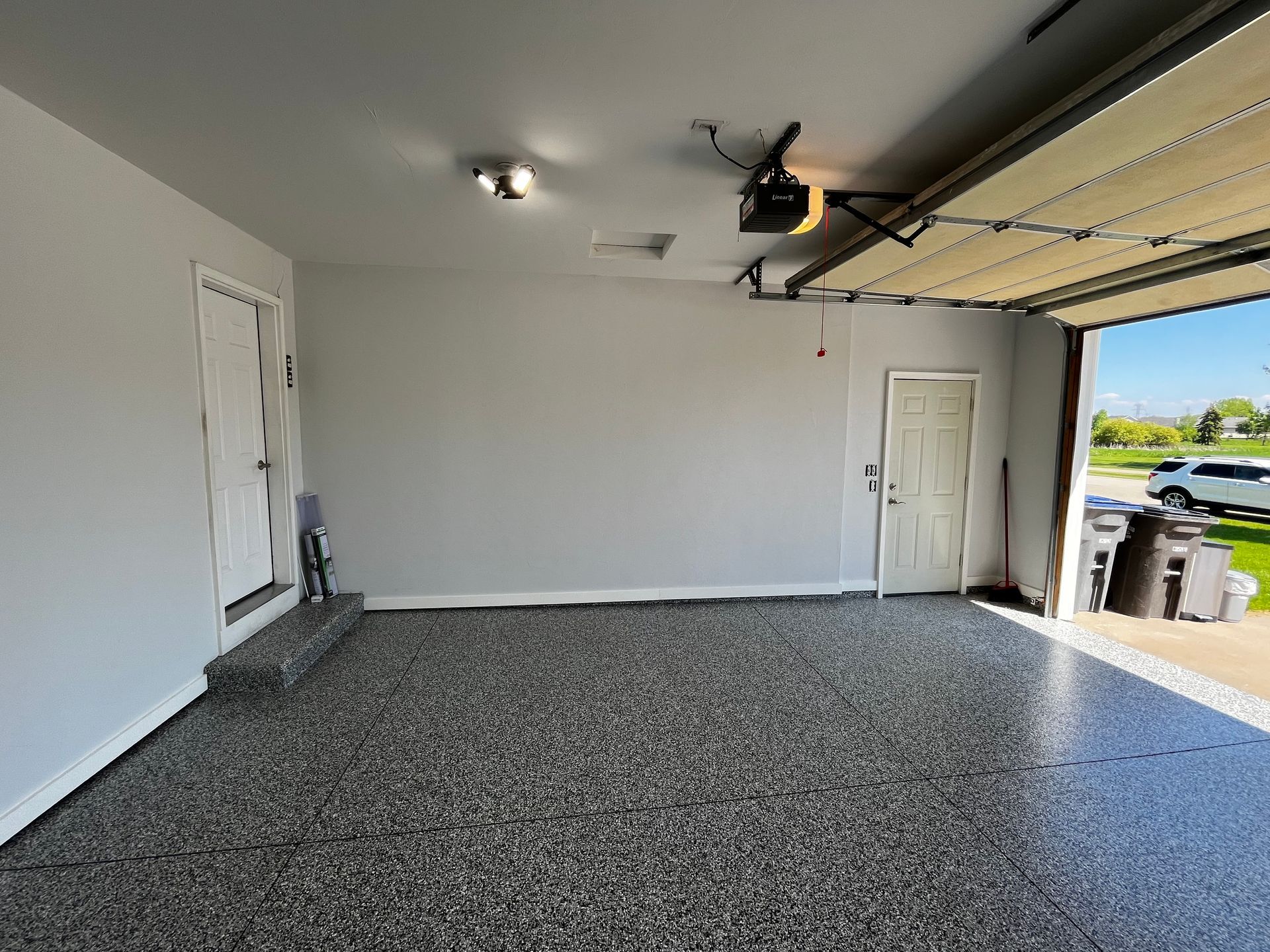 A garage with a garage door open and a gray floor.