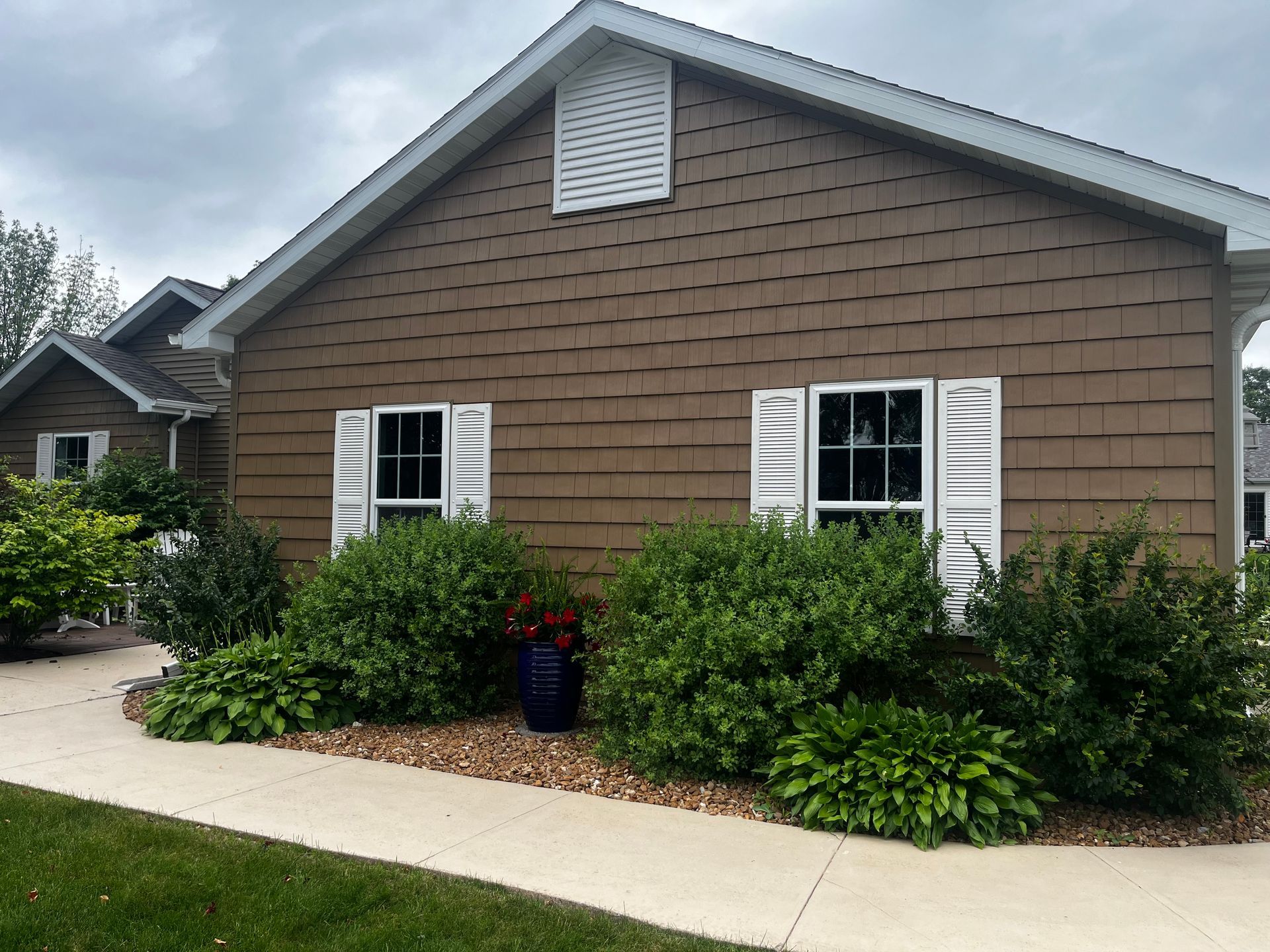 A brown house with white shutters on the windows