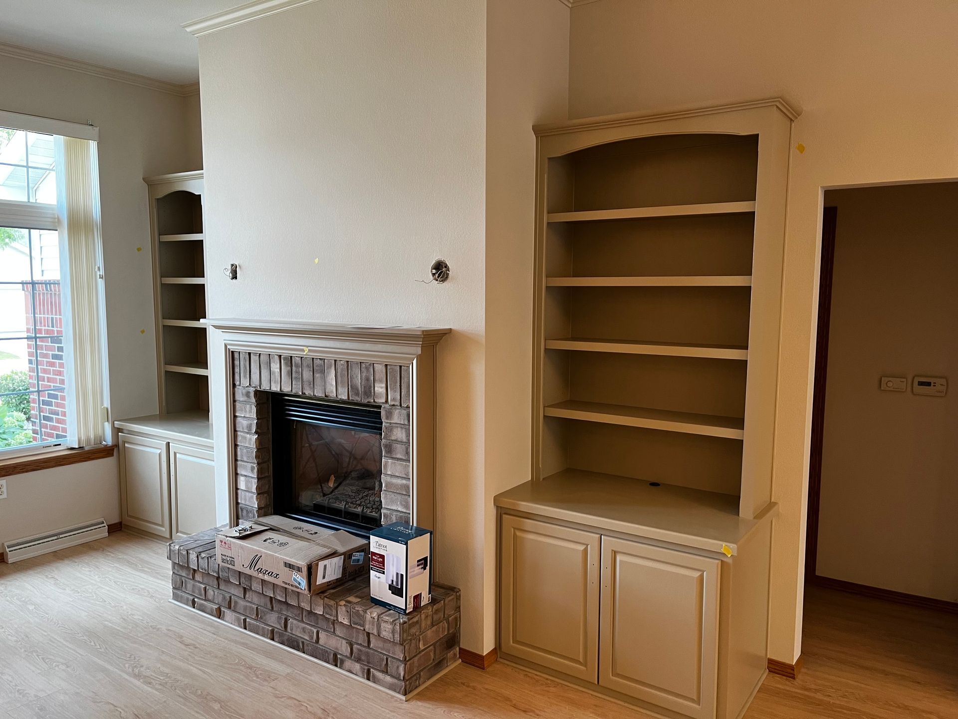 An empty living room with a fireplace and shelves