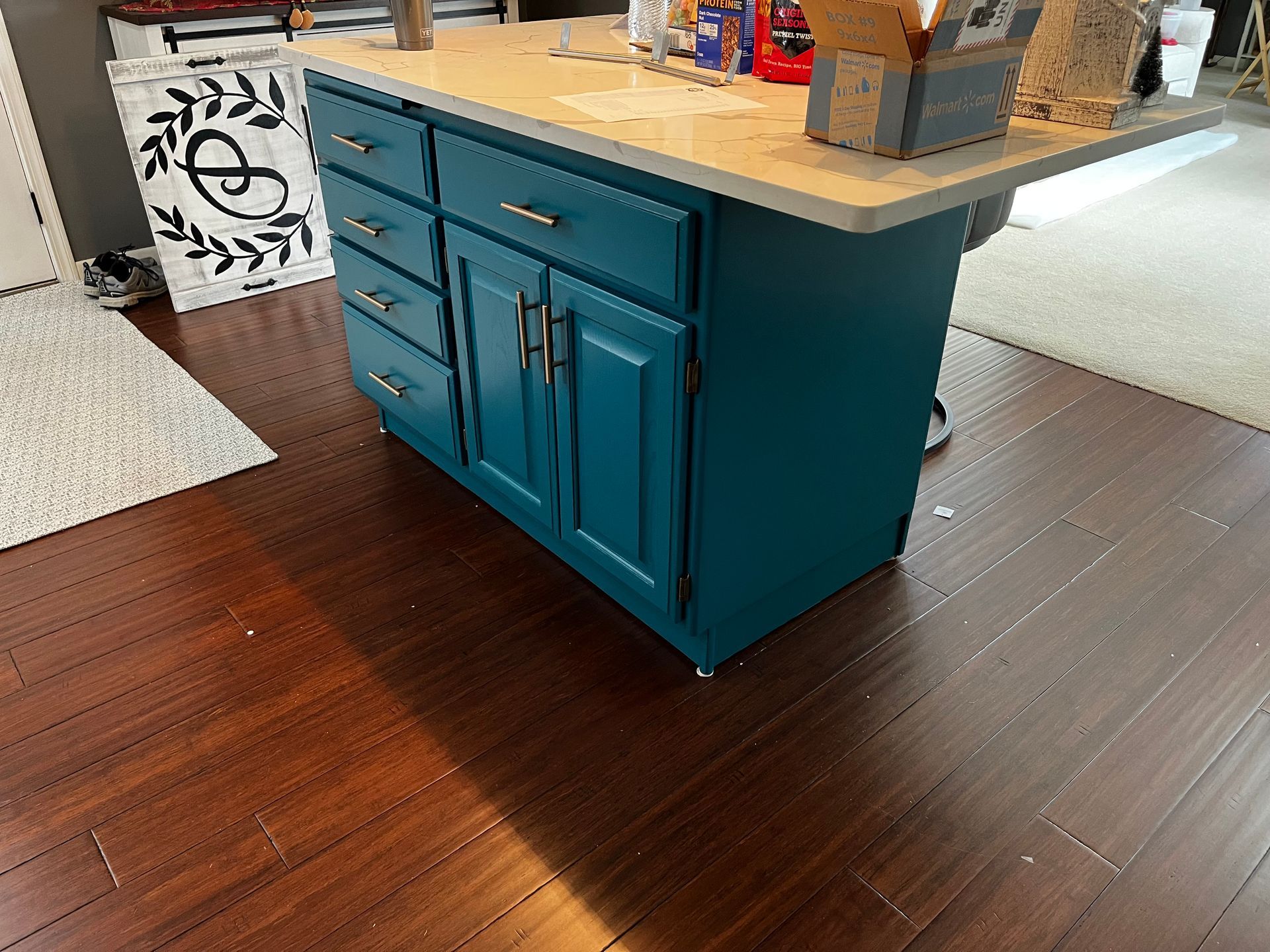 A blue cabinet is sitting on a wooden floor in a kitchen.