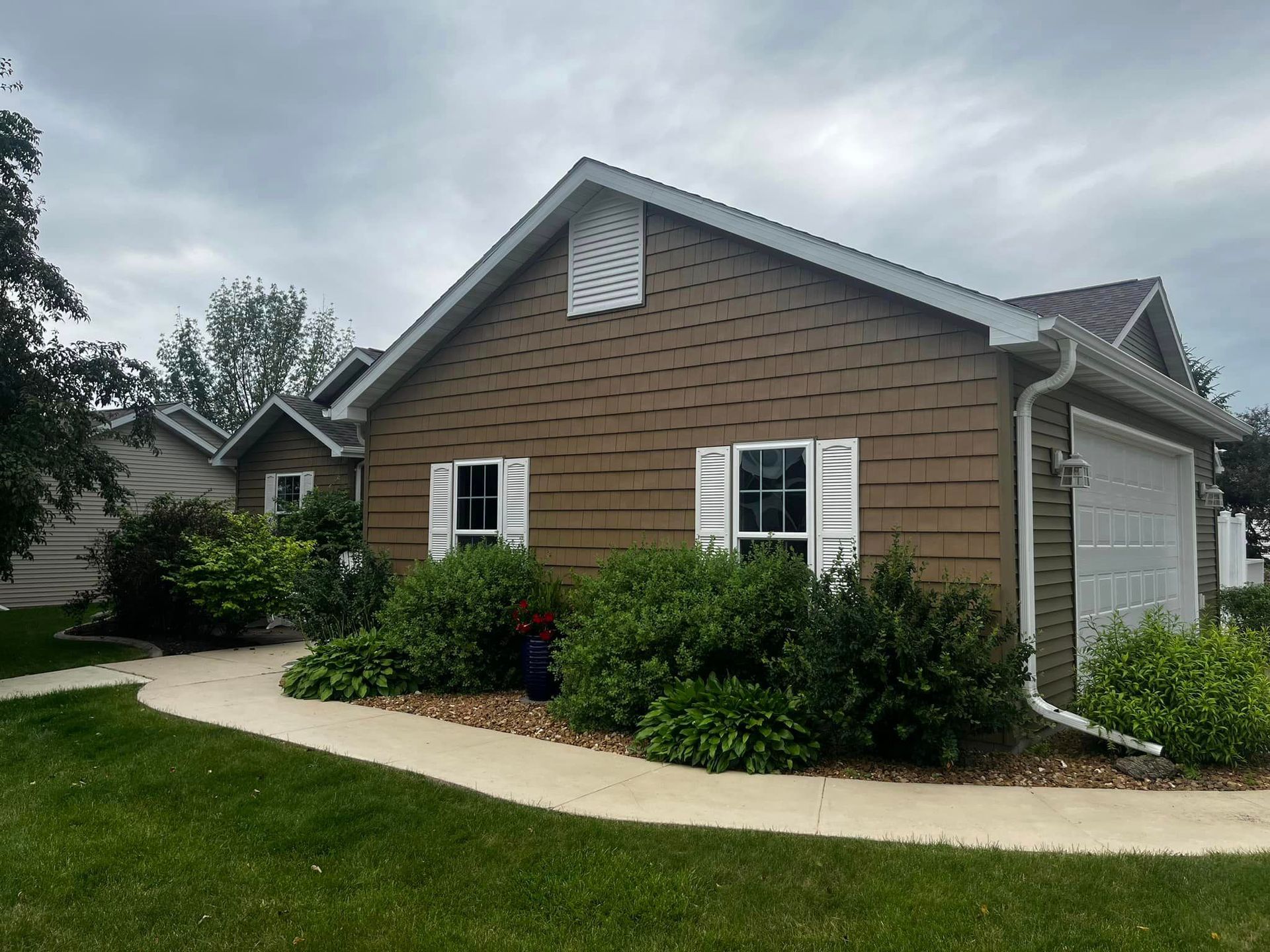 A brown house with white shutters and a white garage door