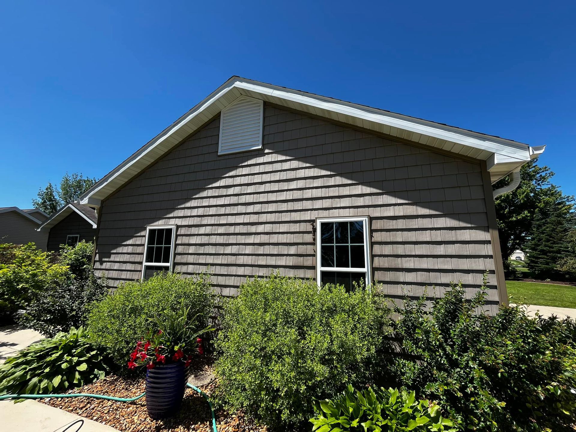A house with a lot of windows and bushes in front of it.