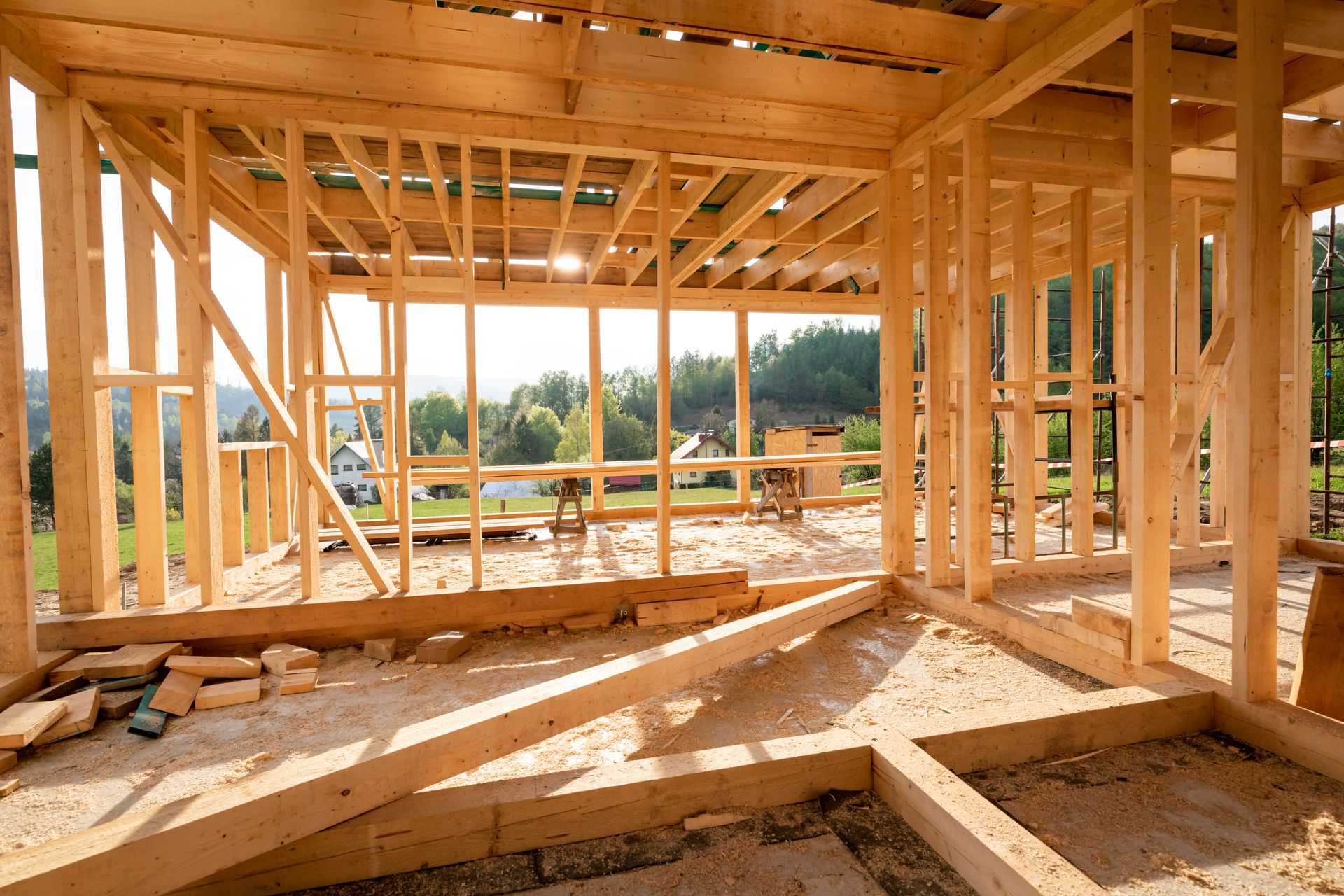 Wooden frame of a house under construction; open to a sunny outdoor view.