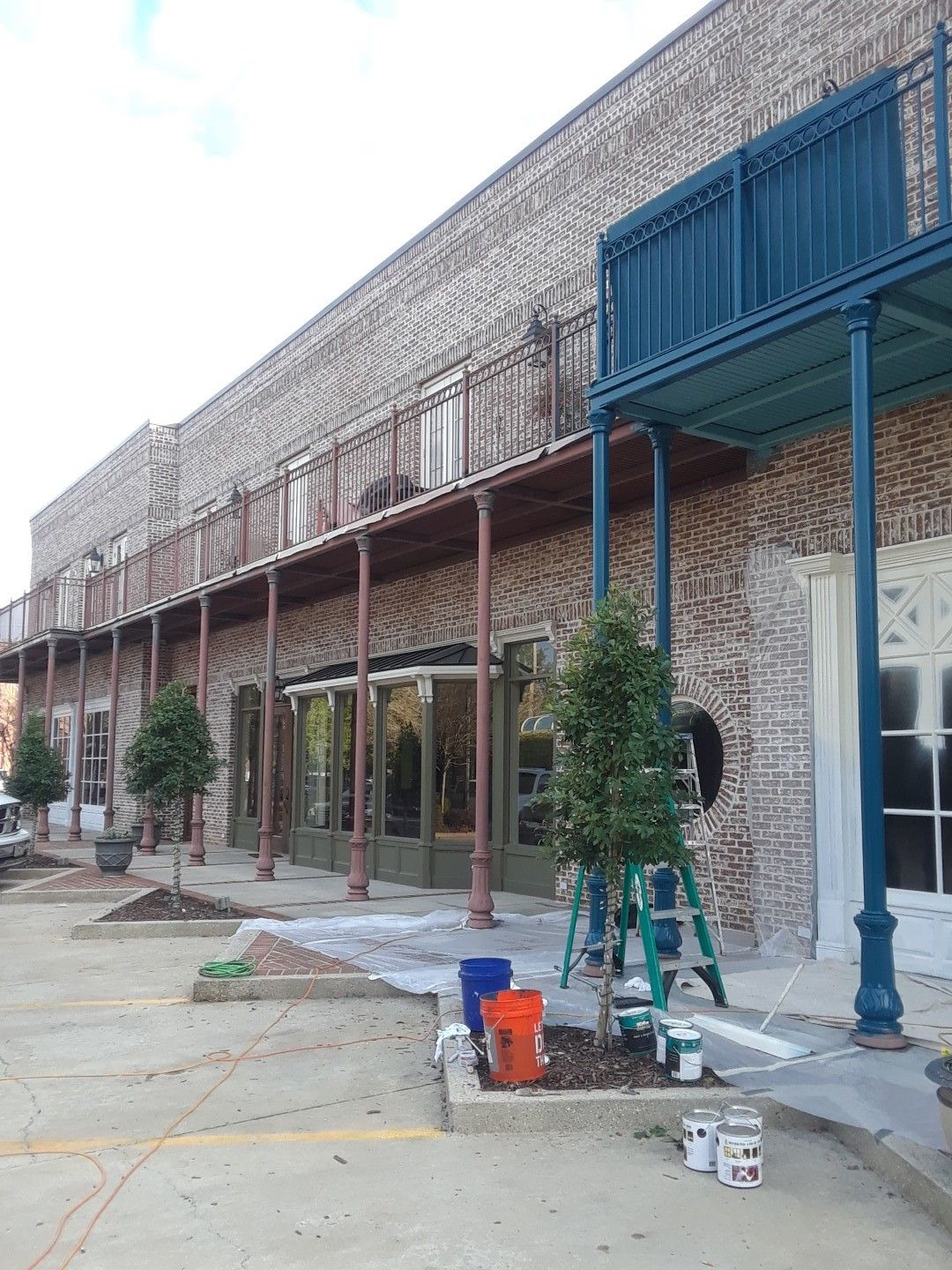 A brick building with a blue balcony is being painted